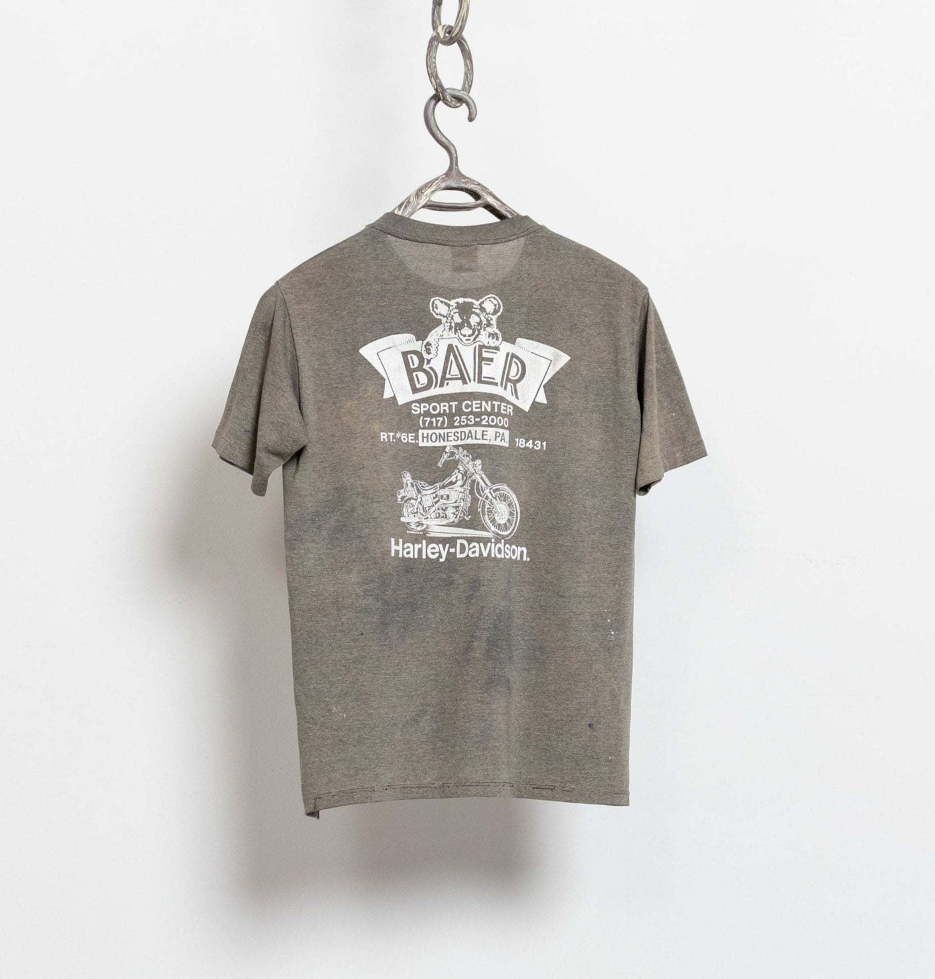 Gray t-shirt with white graphic design on a hanger against a white background