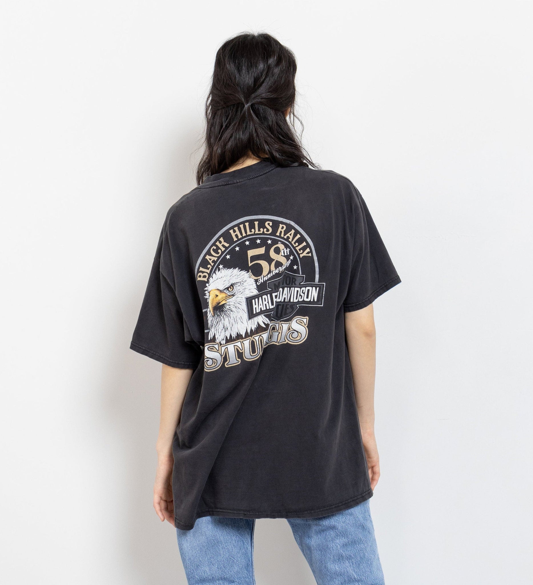 A person wearing a vintage Harley Davidson t-shirt with graphics on the front and back, featuring an eagle and text related to the Sturgis rally.