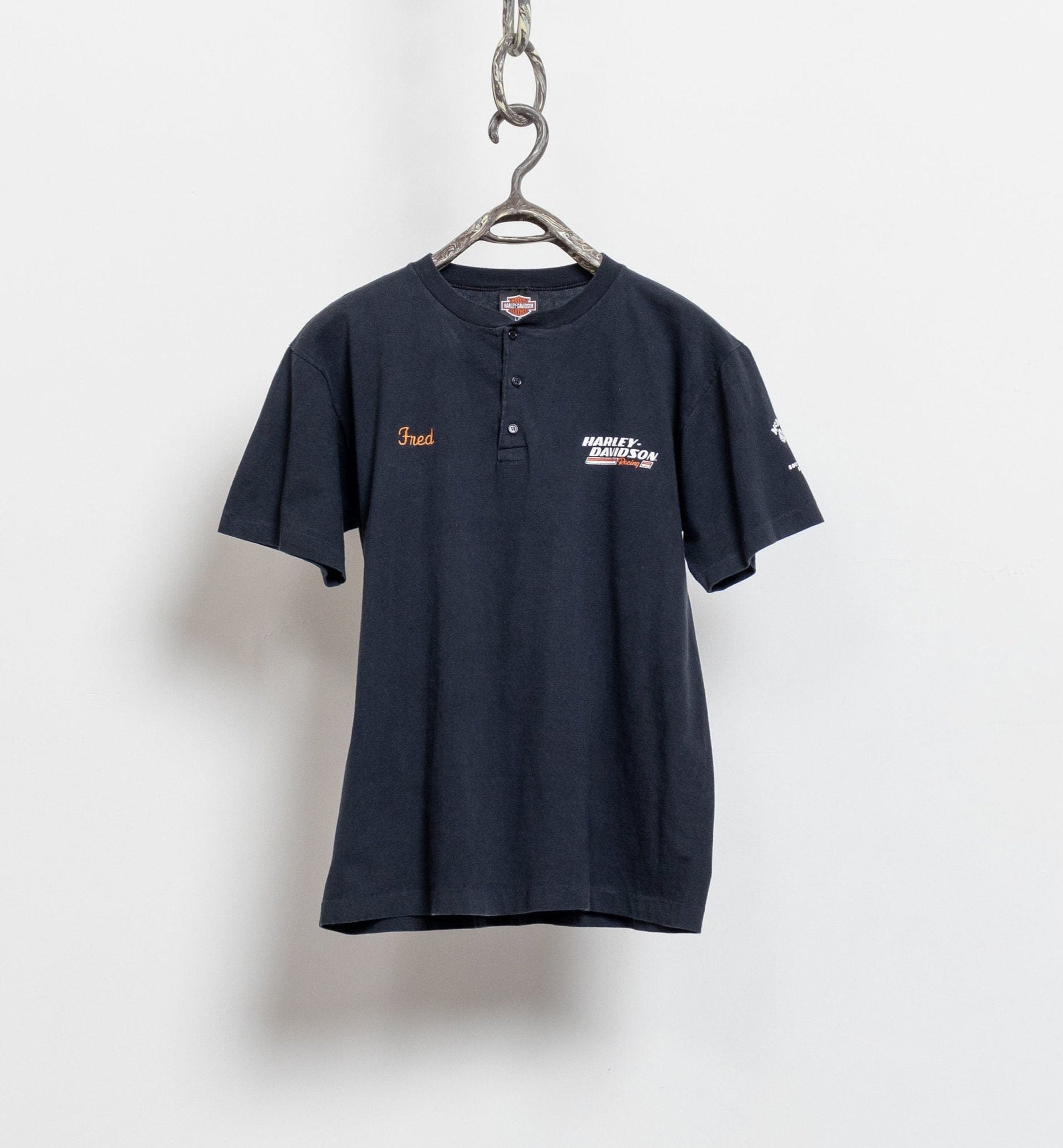 Black t-shirt with logos on a hanger against a white background