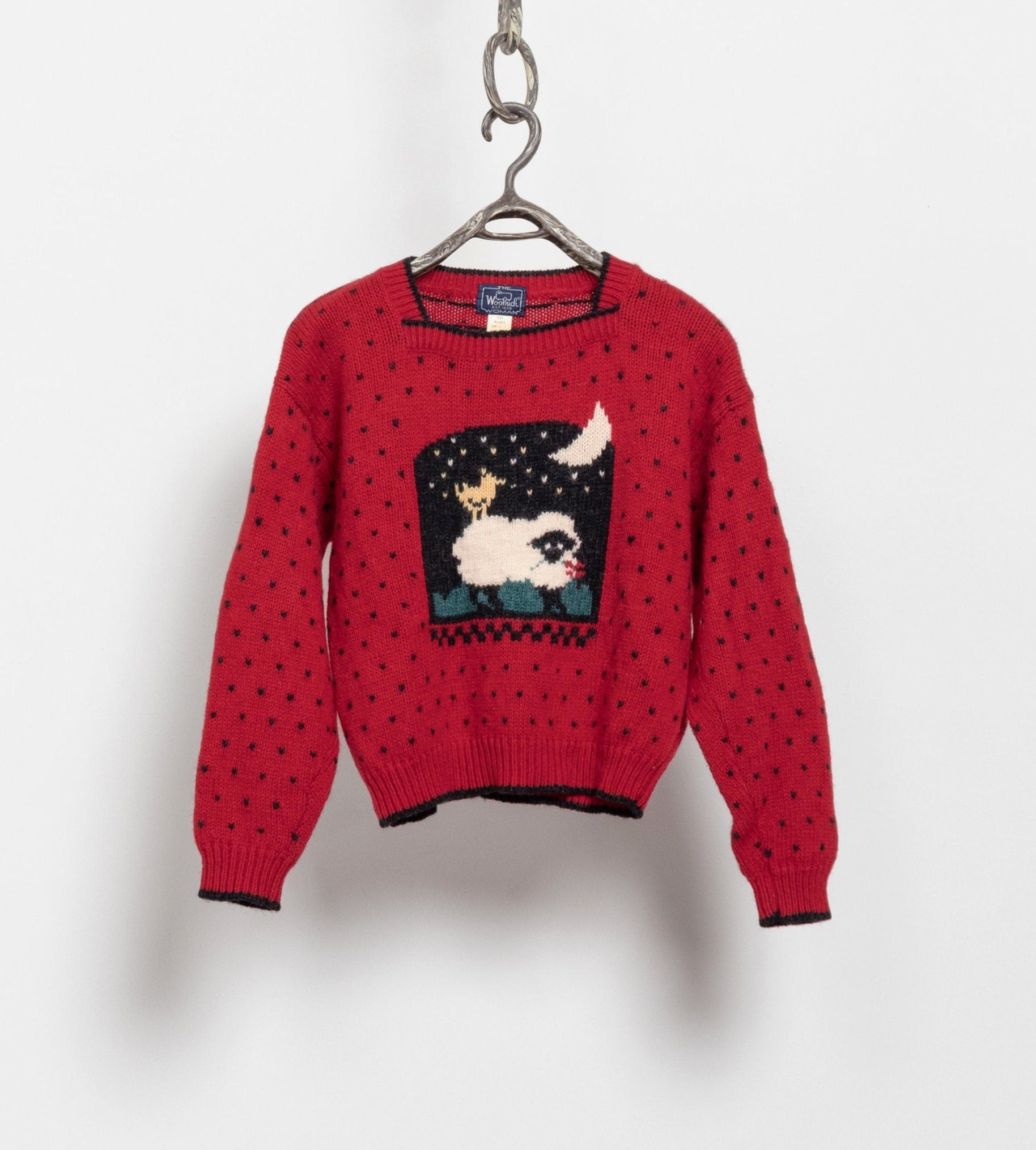 A red wool knit sweater with a square neckline and an allover polka dot design that features a silhouette of a sheep and a bird.