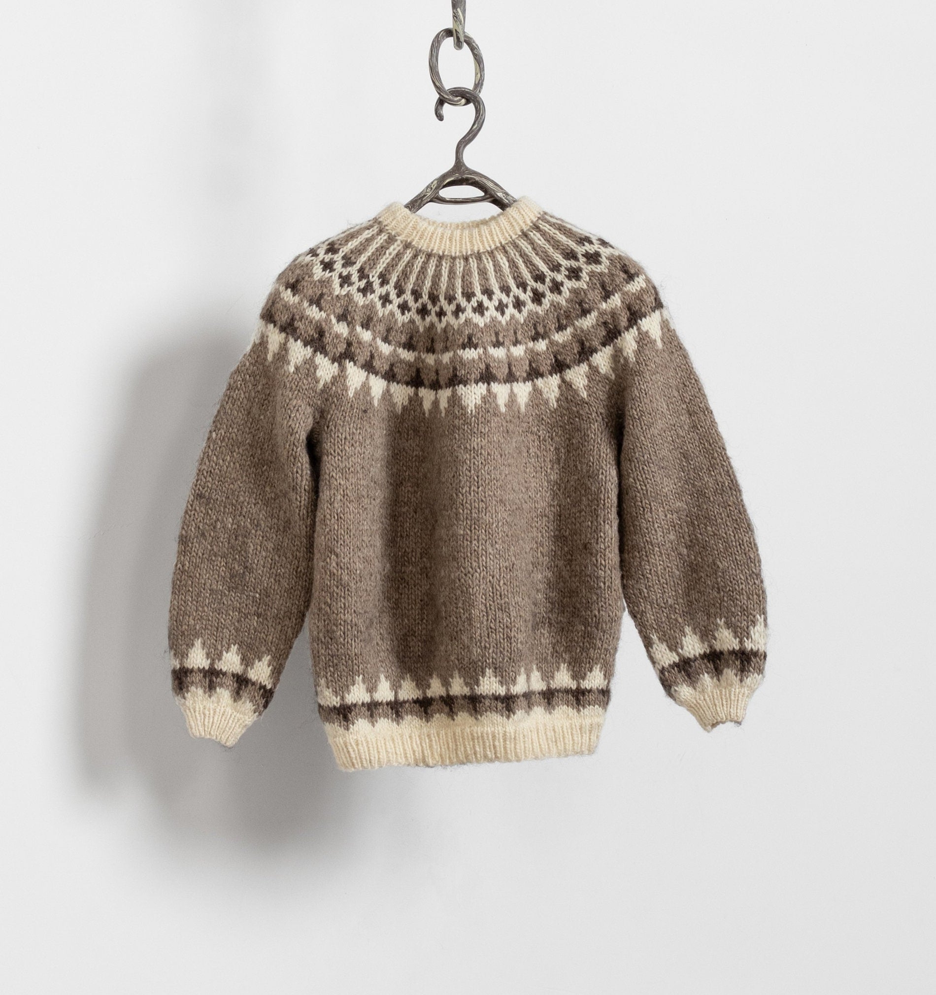 A vintage fair isle knit pattern sweater in beige and brown tones, displayed on a hanger against a white background.