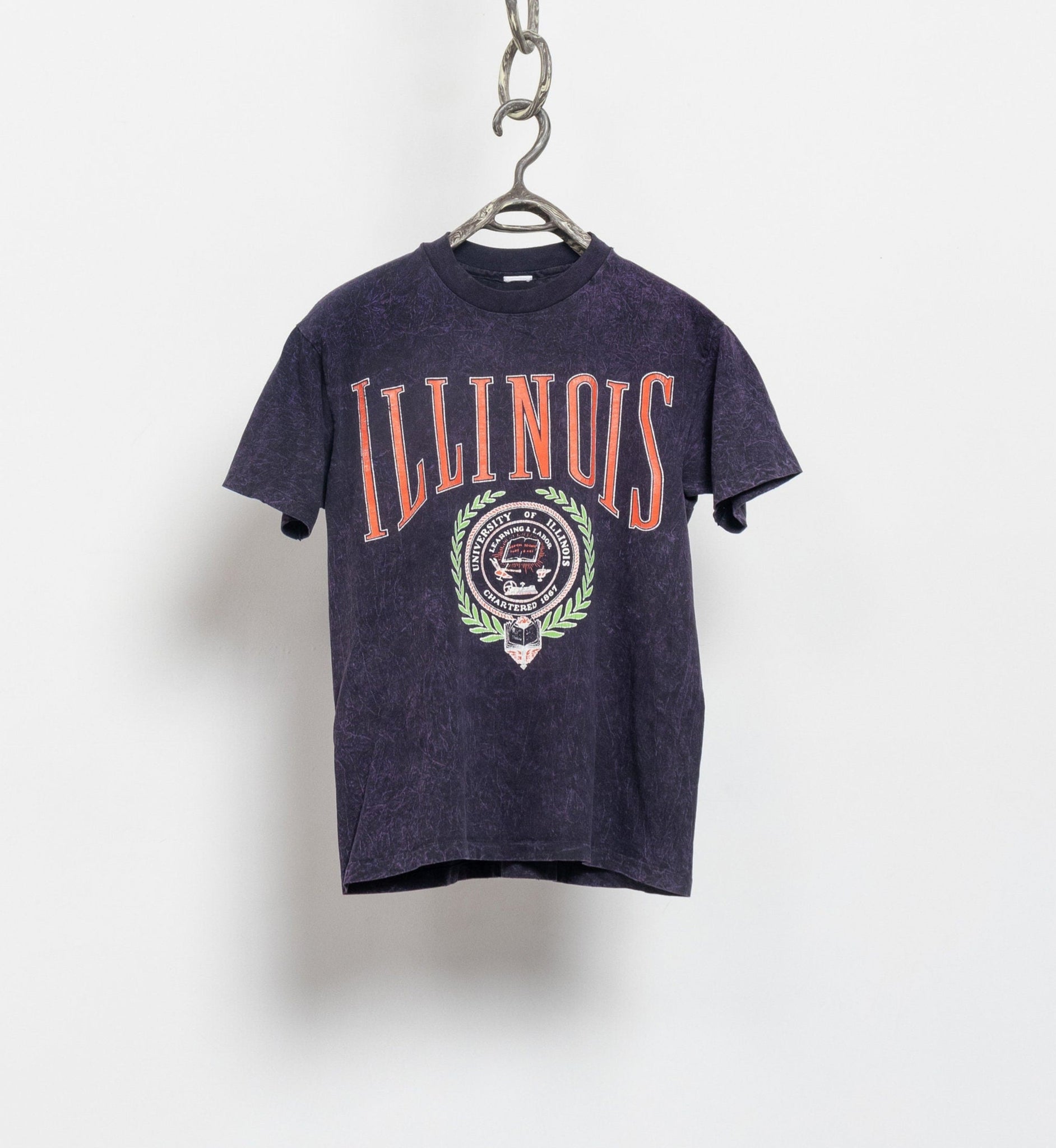 Black t-shirt with 'ILLINOIS' printed on it, hanging against a white background
