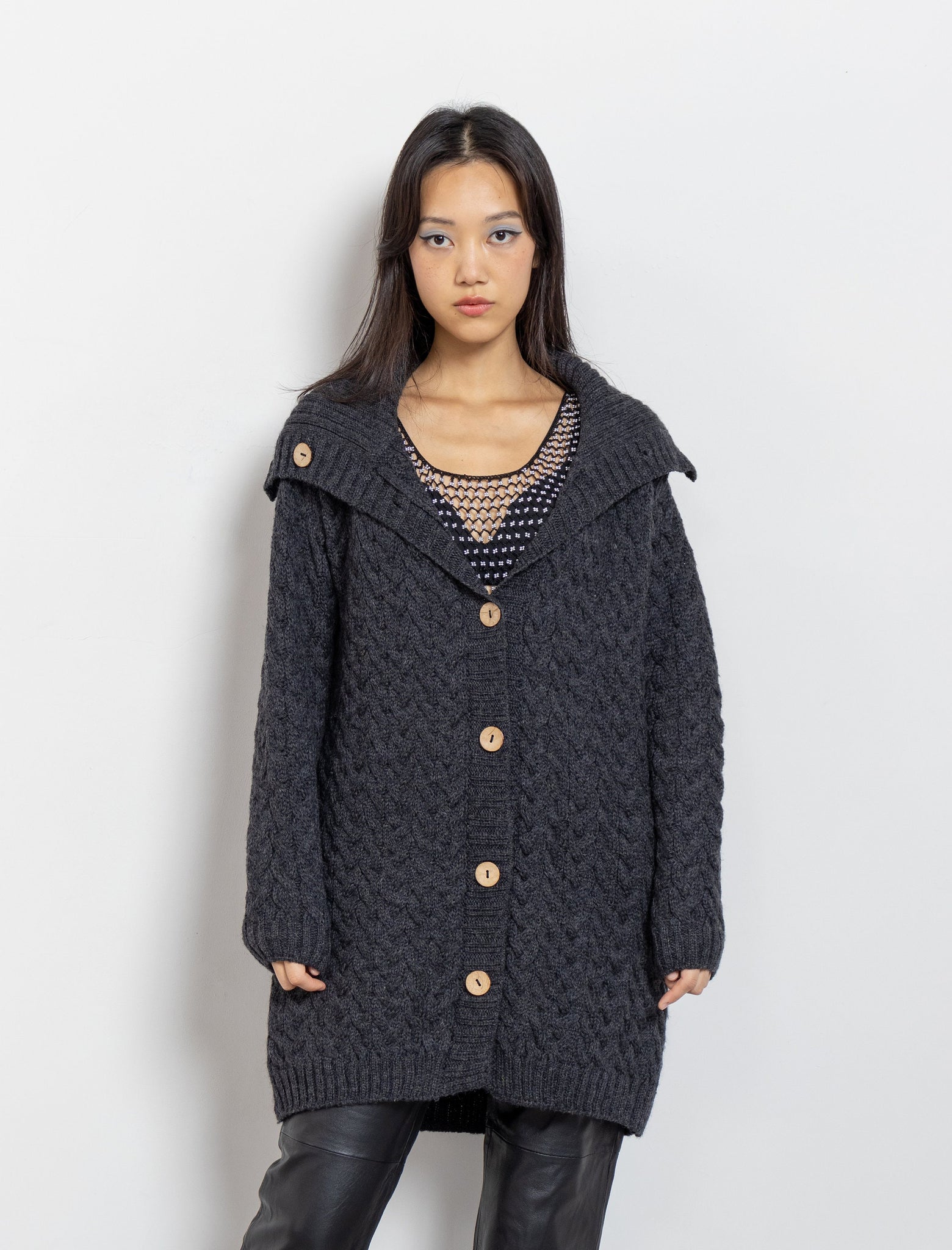 A female model wearing a vintage 90's dark heather grey button up cardigan with a high neck and long sleeves.