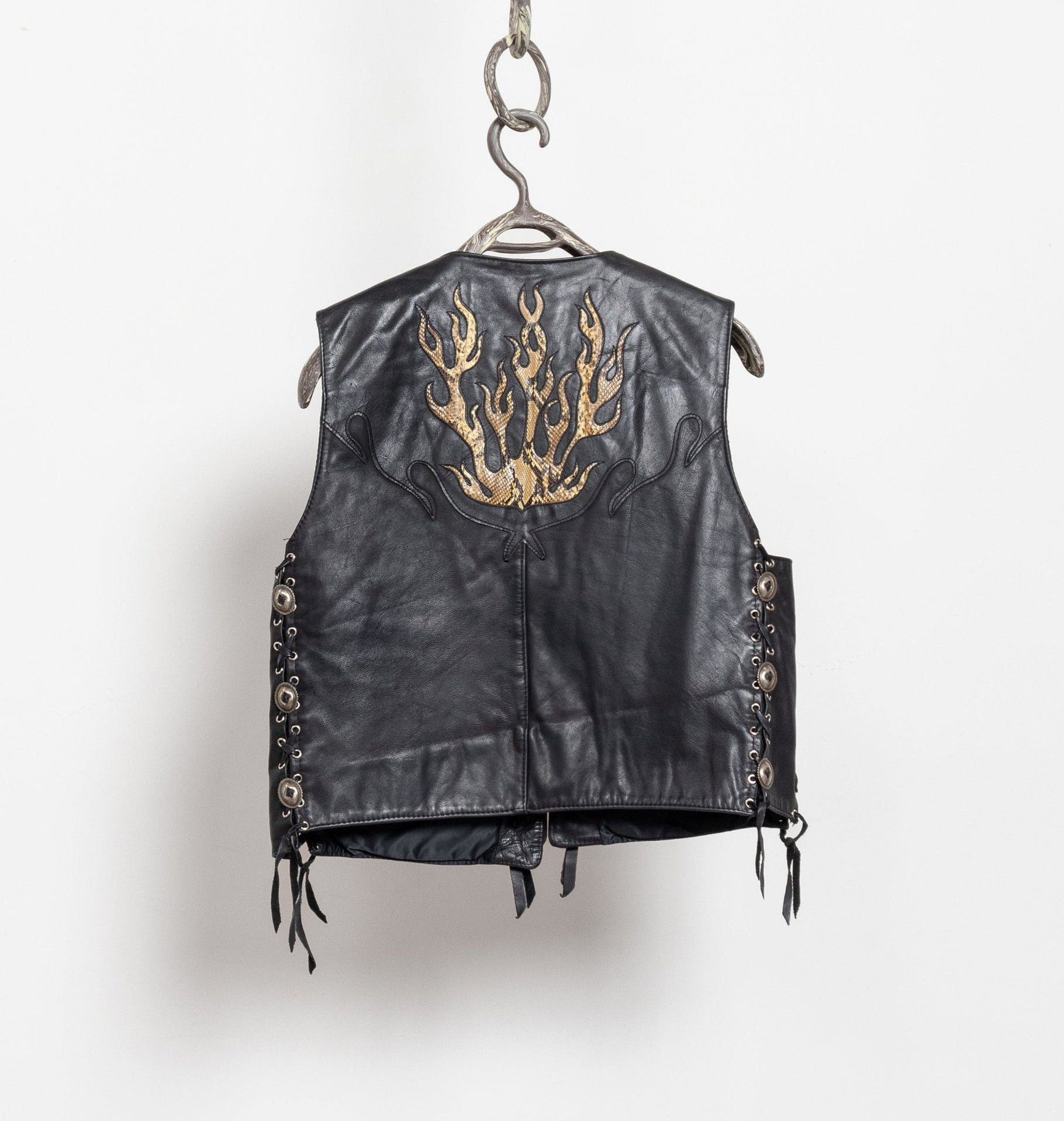 Black leather vest with gold embroidery on a hanger against a white background