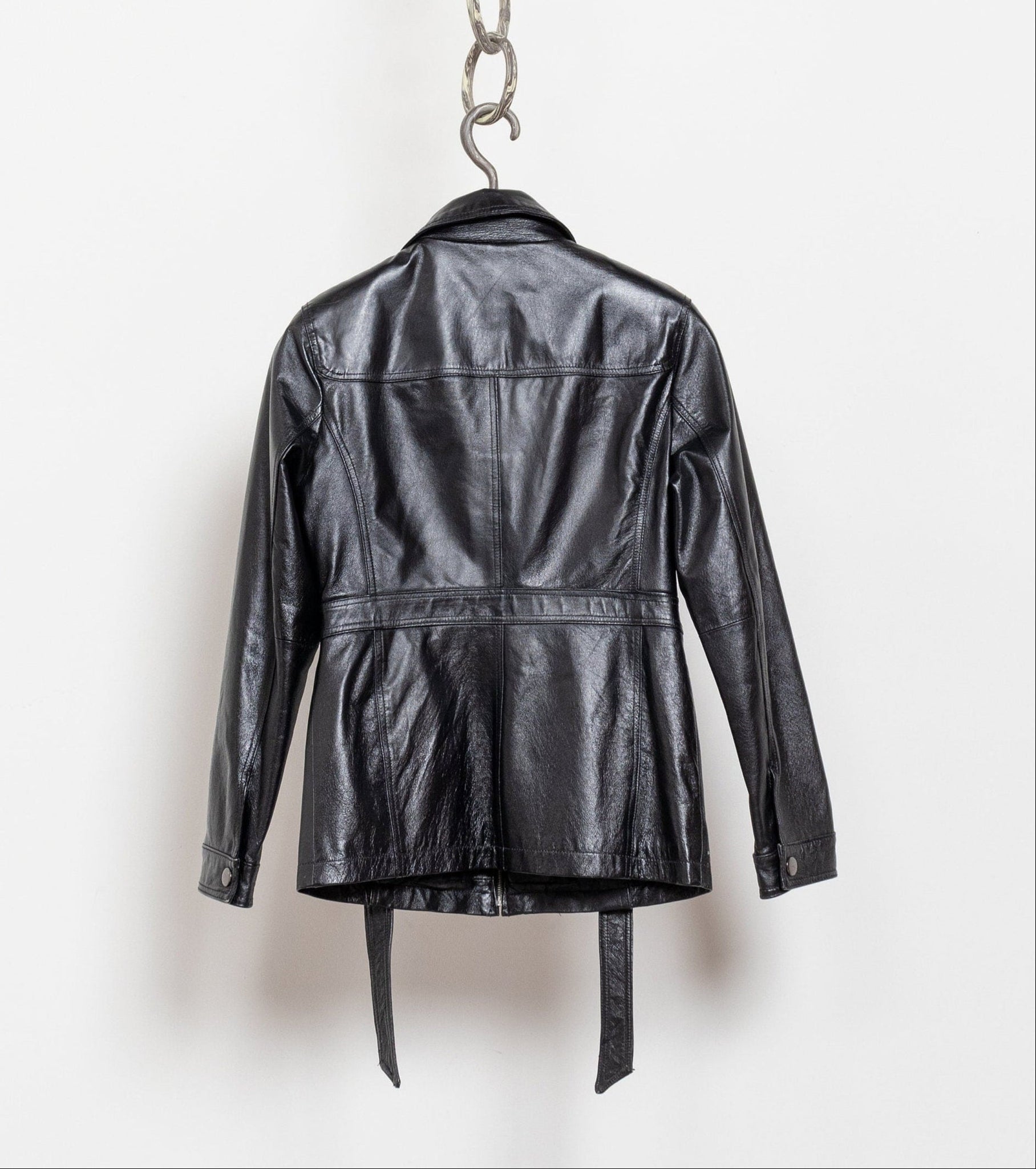 Black leather jacket hanging on a chain against a white background
