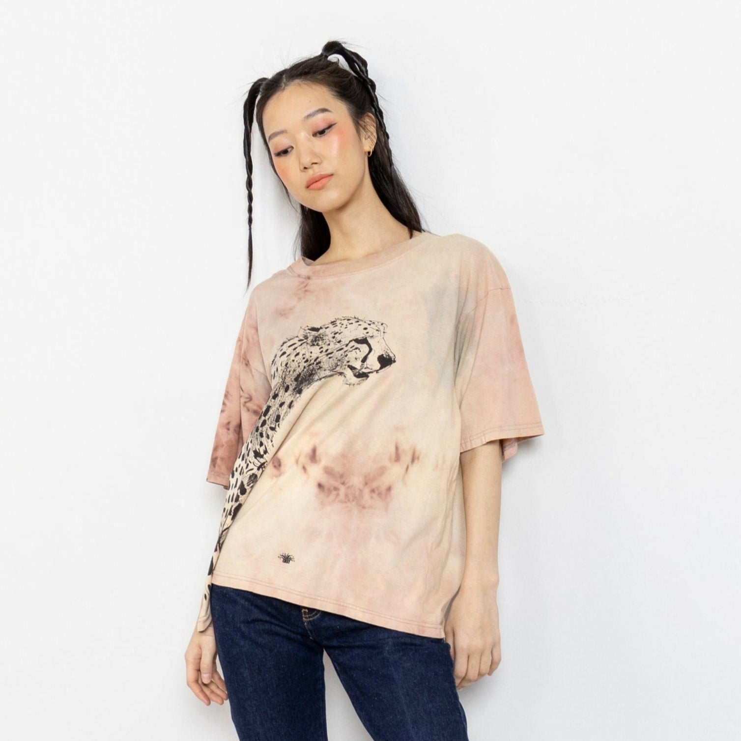 A person wearing a beige tie-dye t-shirt with a leopard graphic, paired with blue jeans.