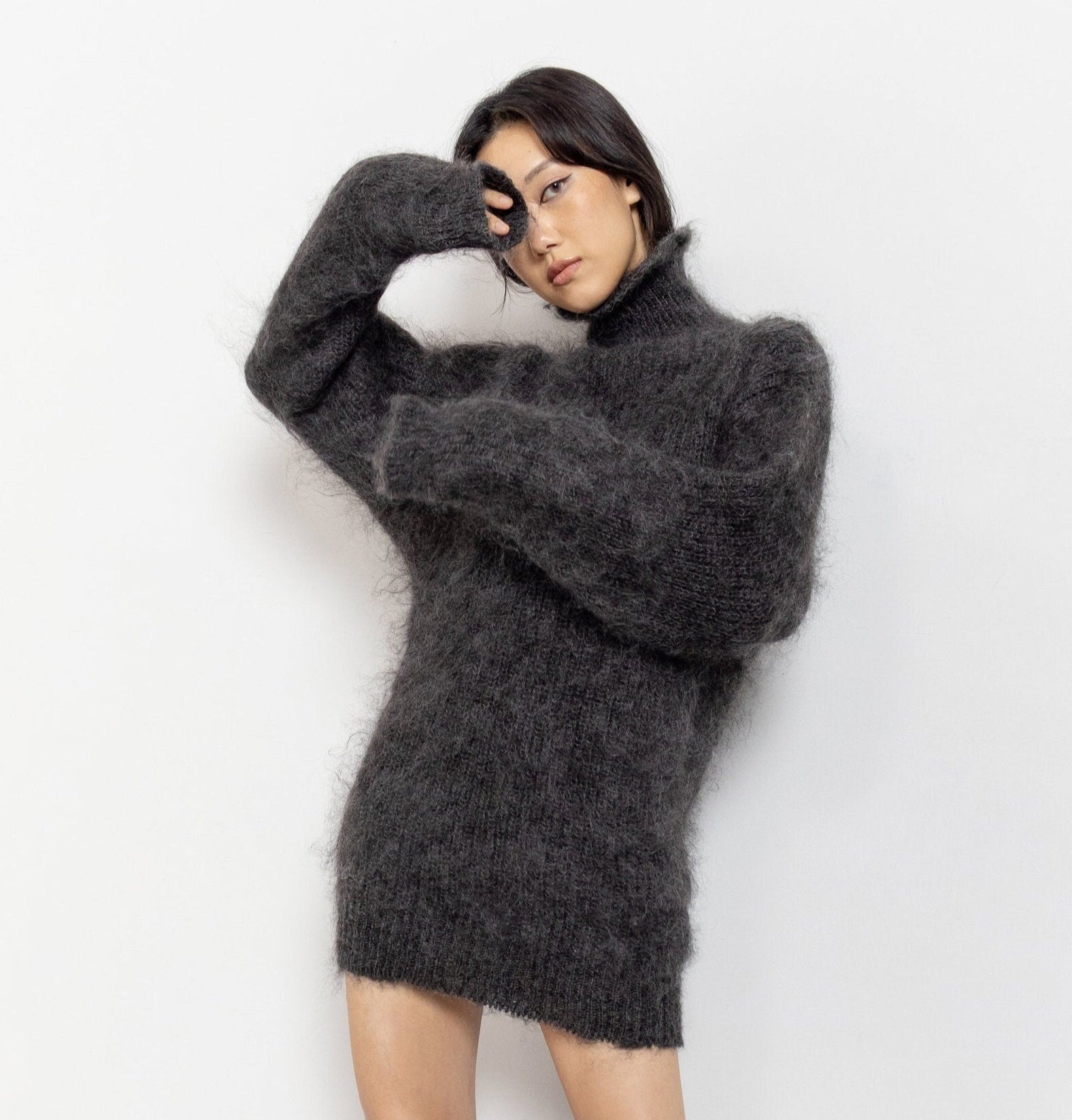 A person wearing a long, grey mohair turtleneck sweater that reaches mid-thigh.