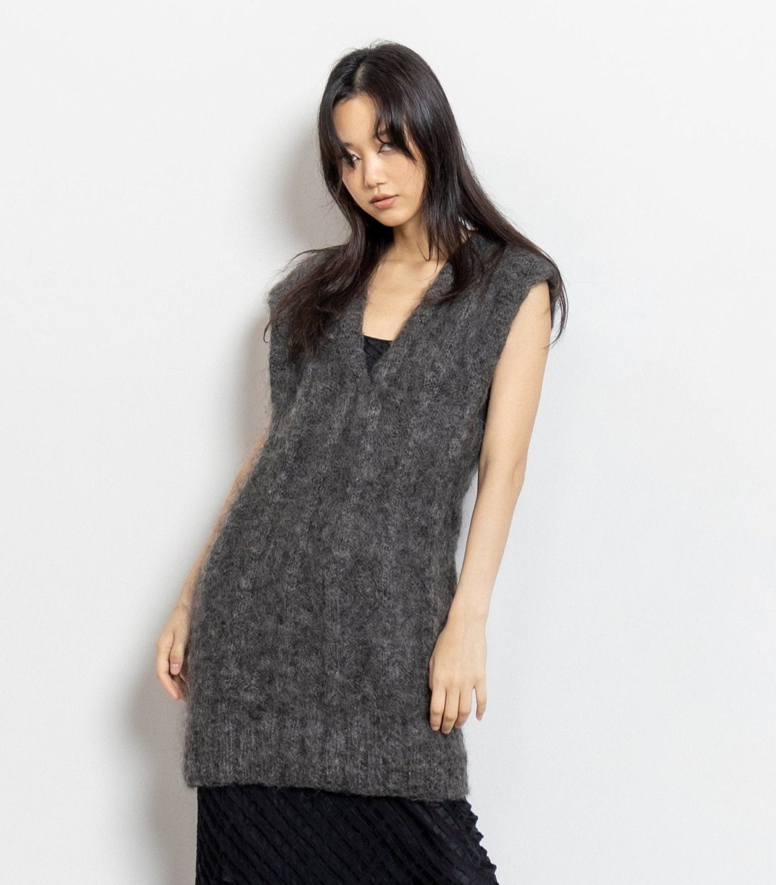 Woman wearing a gray sleeveless knitted dress against a white background