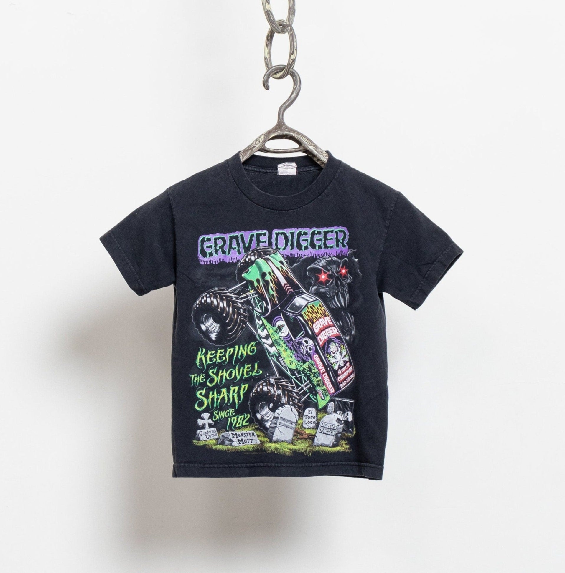 A black Monster Jam t-shirt with a vintage Grave Digger print, hanging from a chain.