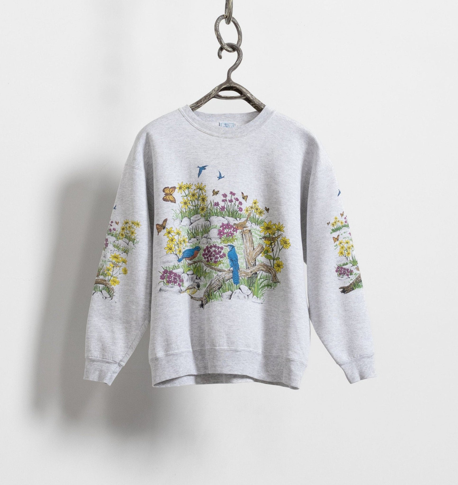 Vintage 90's heather grey cotton print allover bucolic scene graphic sweatshirt displayed on a hanger against a white background.