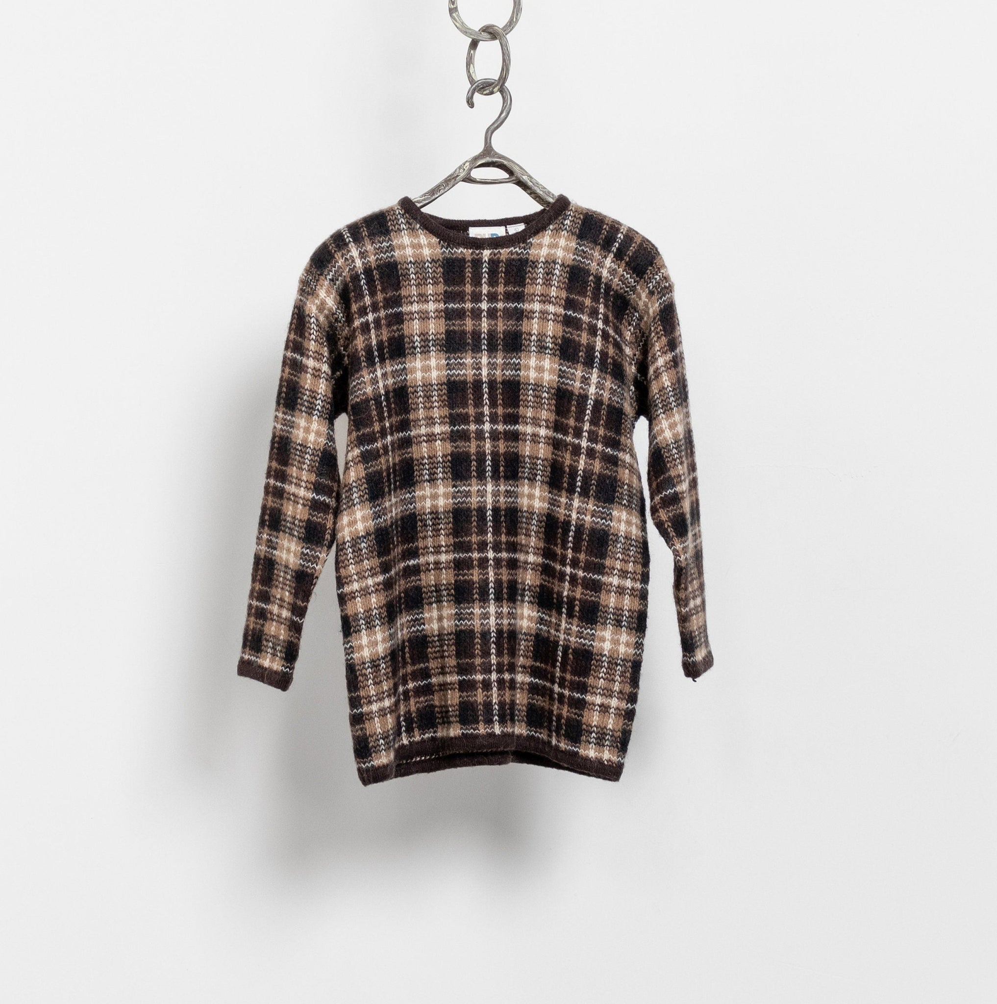 A vintage 90's preppy plaid mohair-blend crew sweater in a classic tartan style, hung on a white wall hook.