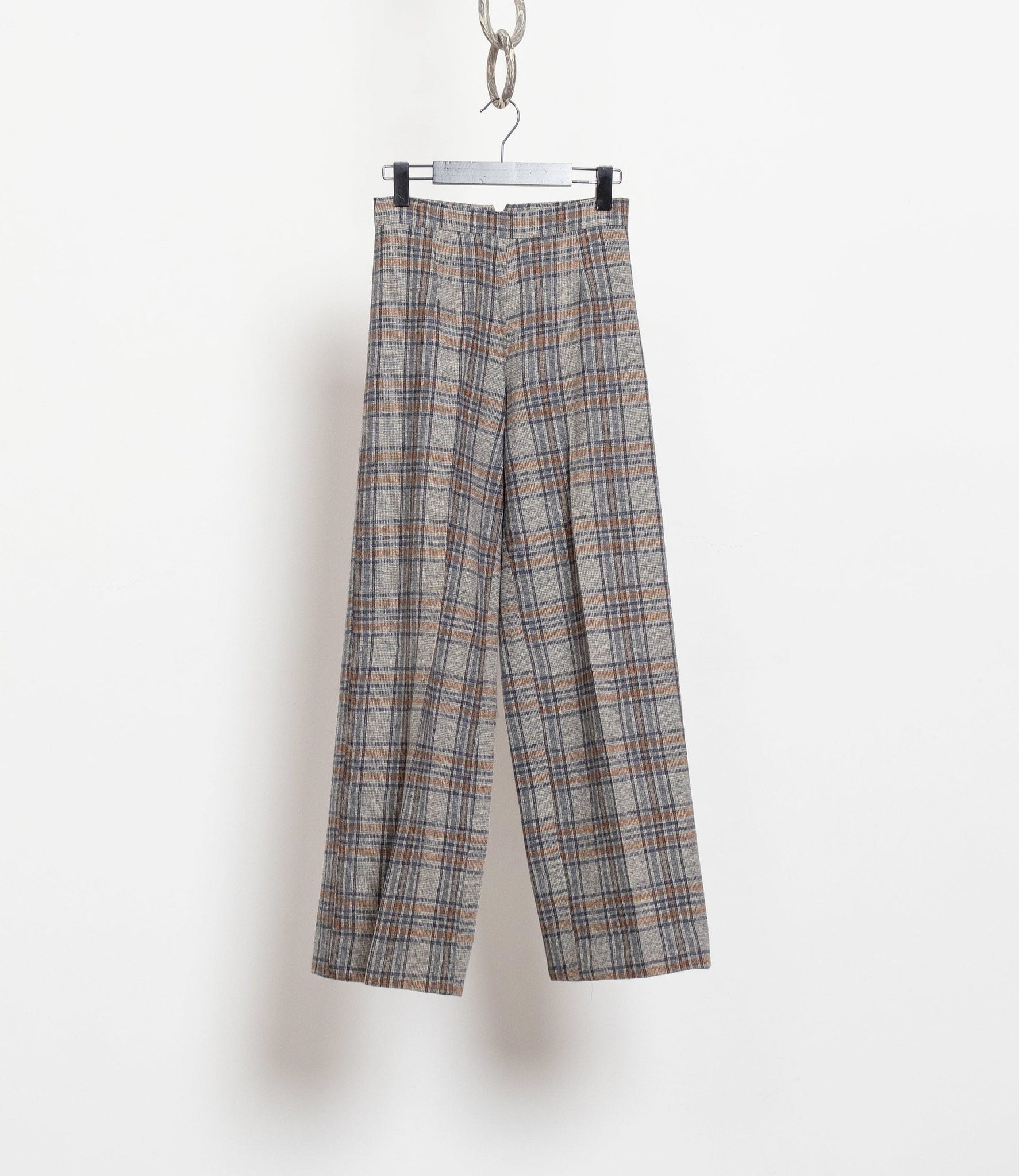 Plaid pants hanging on a rack against a white background