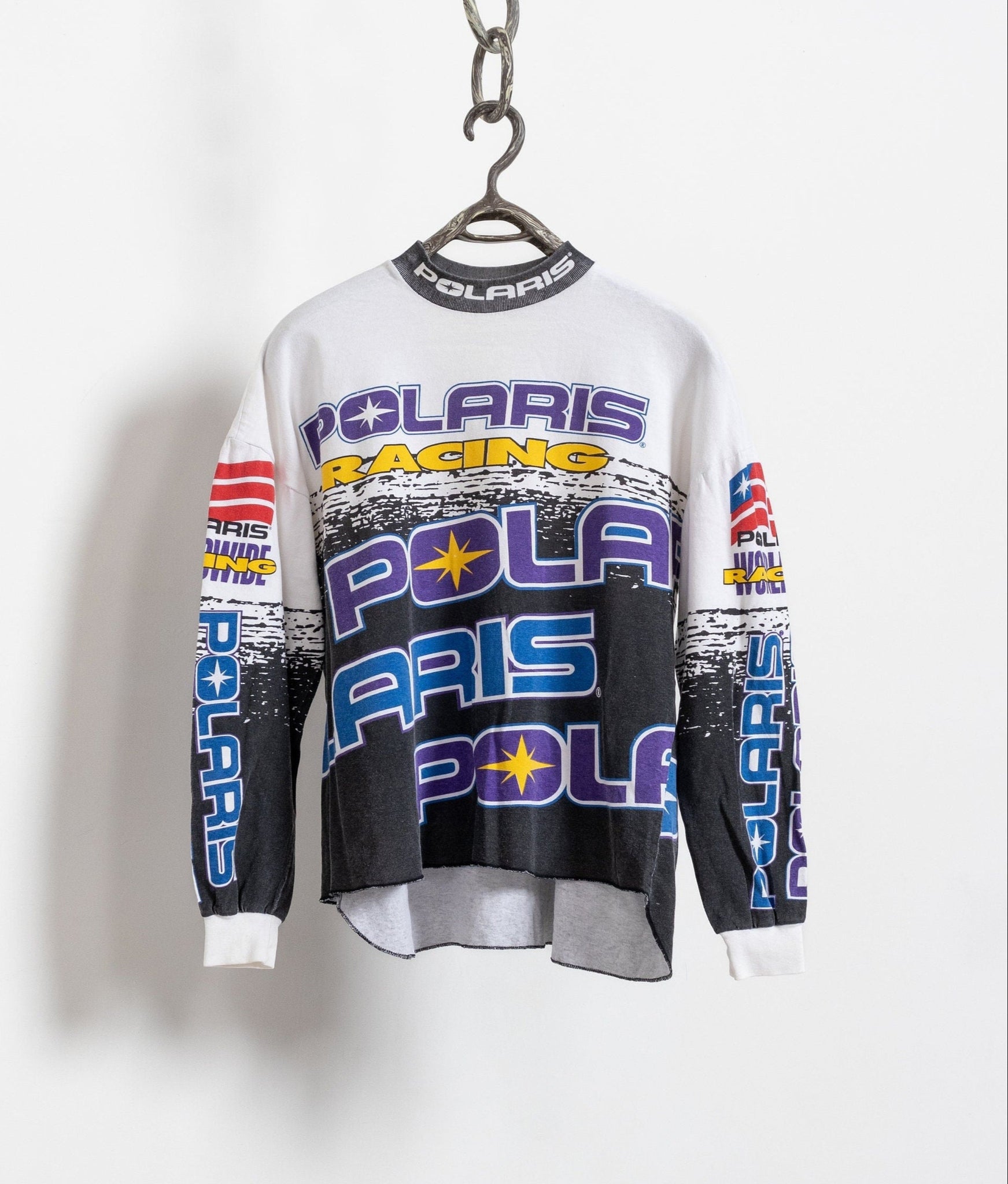 Vintage long sleeve white cotton Polaris print snowmobile tee with vibrant allover graphics, hanging on a hanger against a white background.