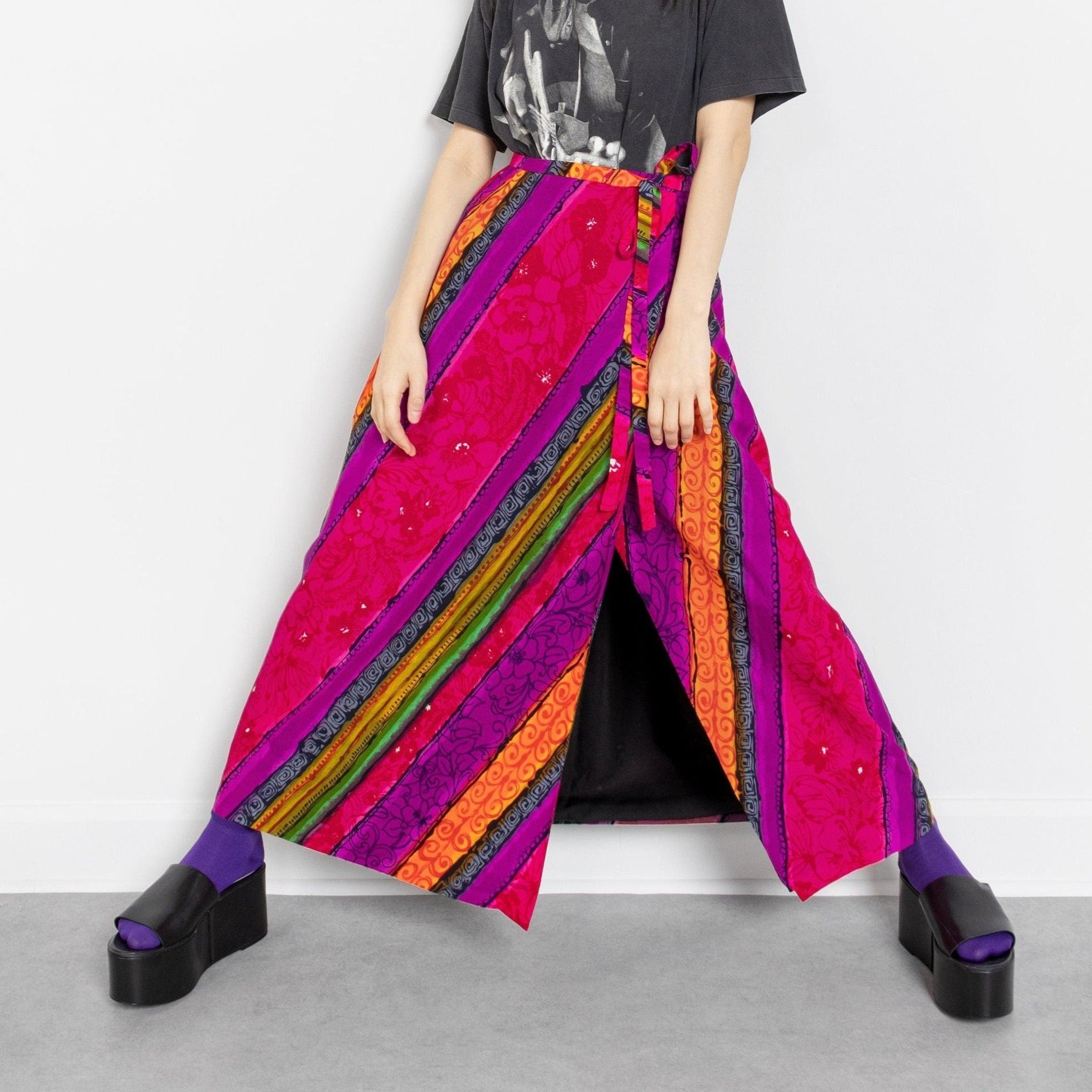 Person wearing a colorful striped skirt and black shirt on a white background