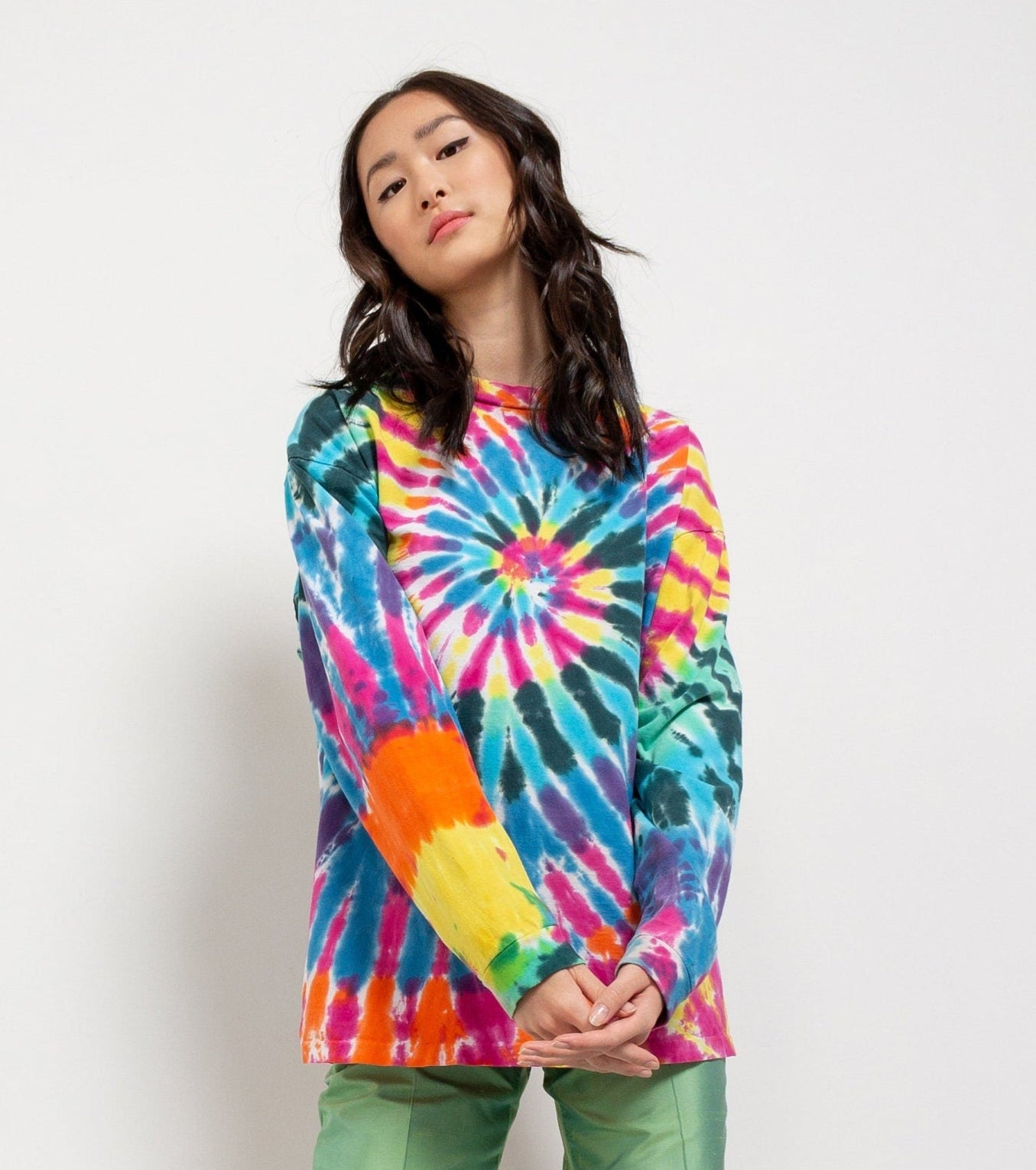 A person wearing a multicolored tie-dye long-sleeve t-shirt with a prominent rainbow design.