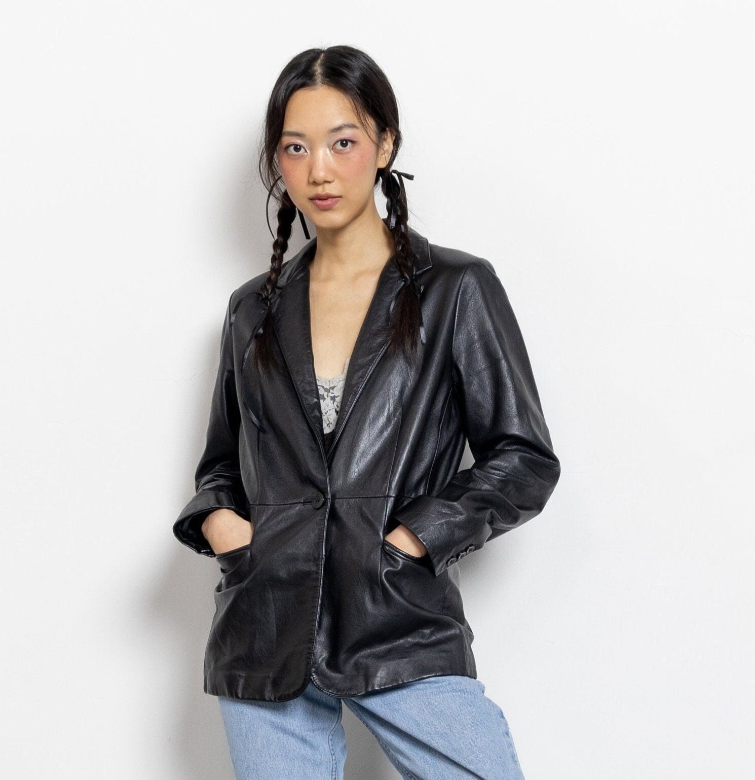Woman wearing a black leather jacket and light blue jeans against a white background