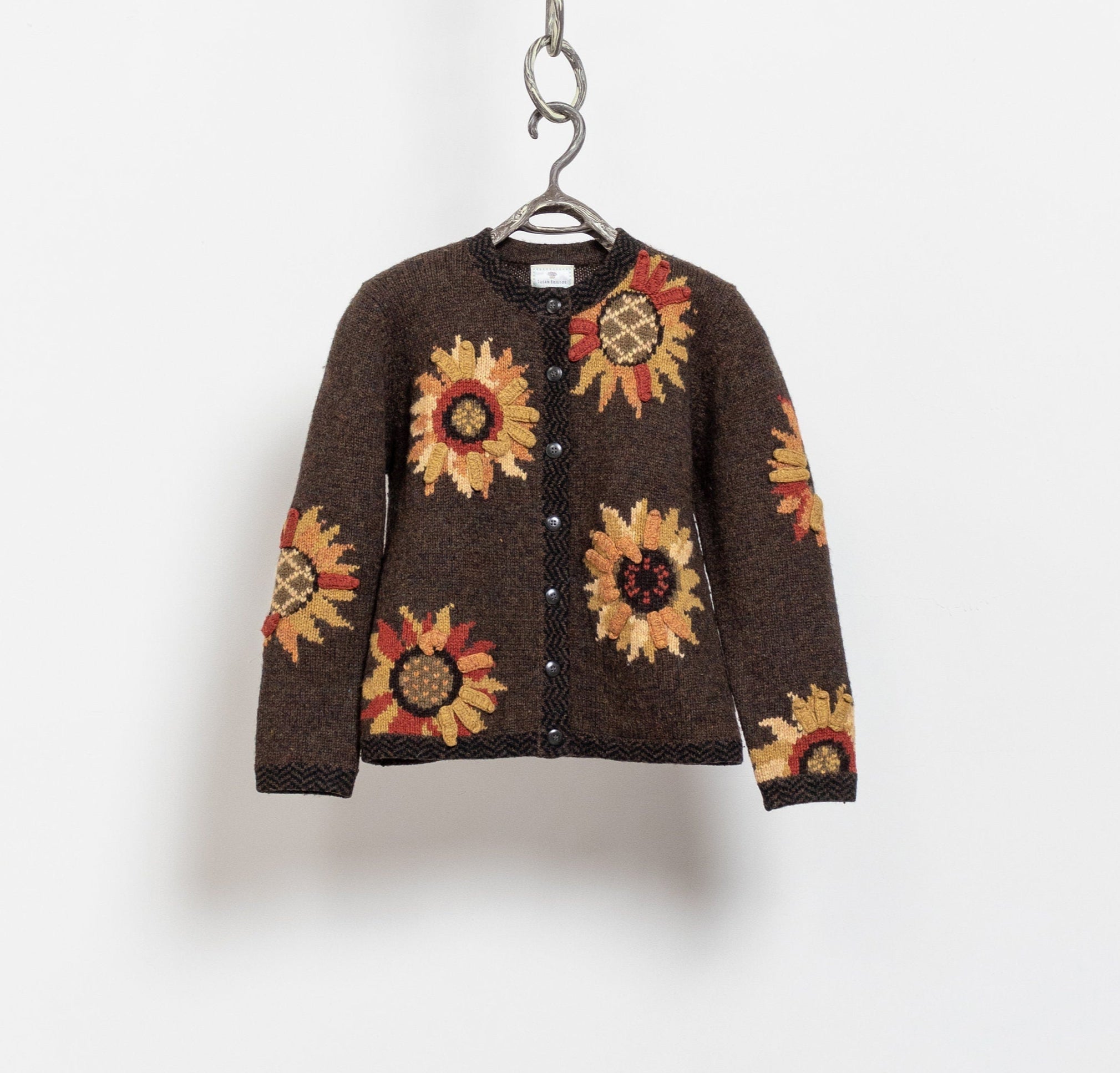 A vintage 90's brown 100% wool embroidered floral knit cardigan with a crew neck, buttons down the front, and shoulder pads. The cardigan features a floral pattern with oversized flowers.