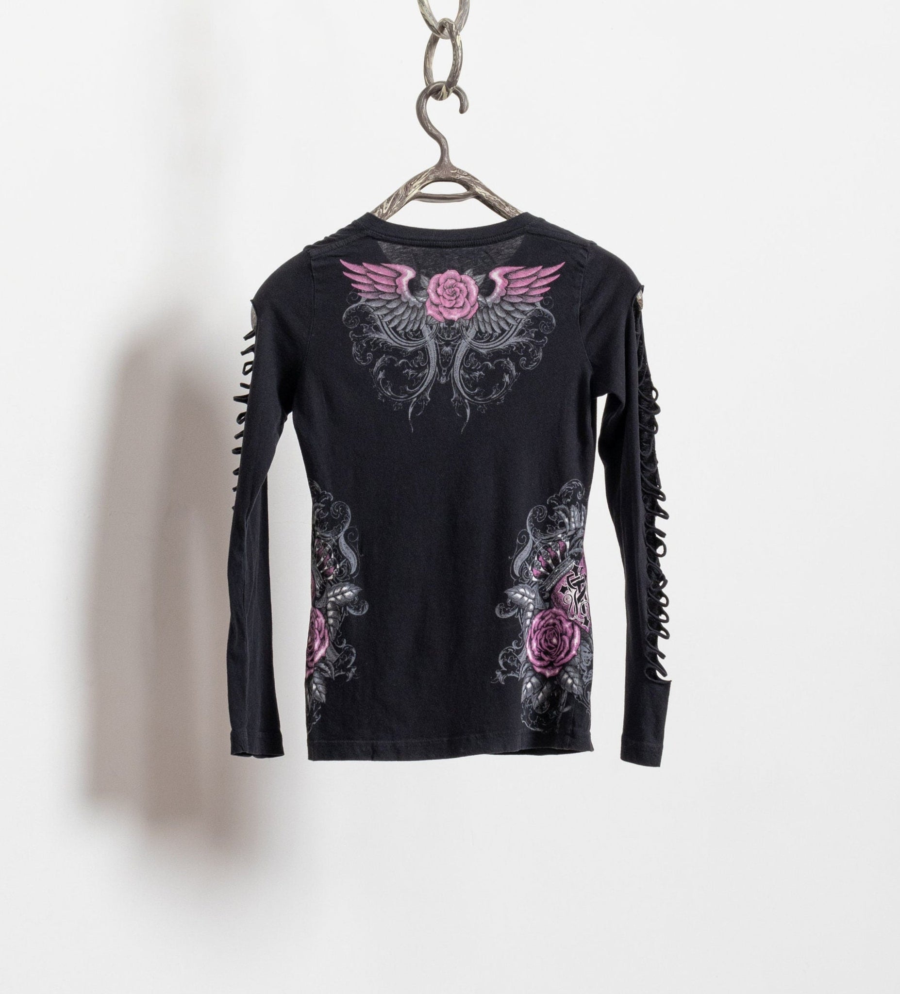 Black long-sleeve shirt with pink floral and wing design on a hanger against a white background