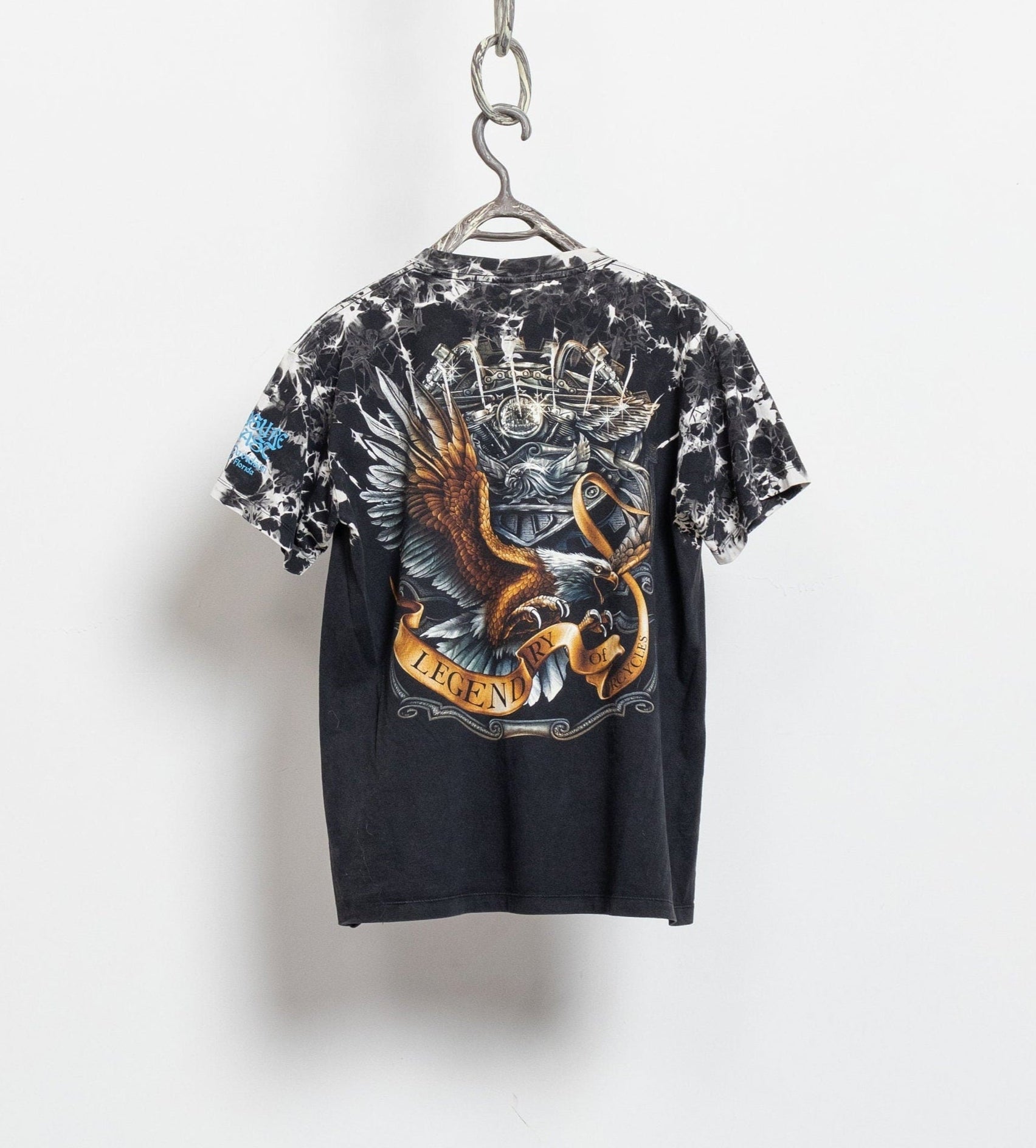 Vintage 90's Harley Davidson tie-dye t-shirt with silver-tone studs and allover print, displayed on a hanger against a white background.