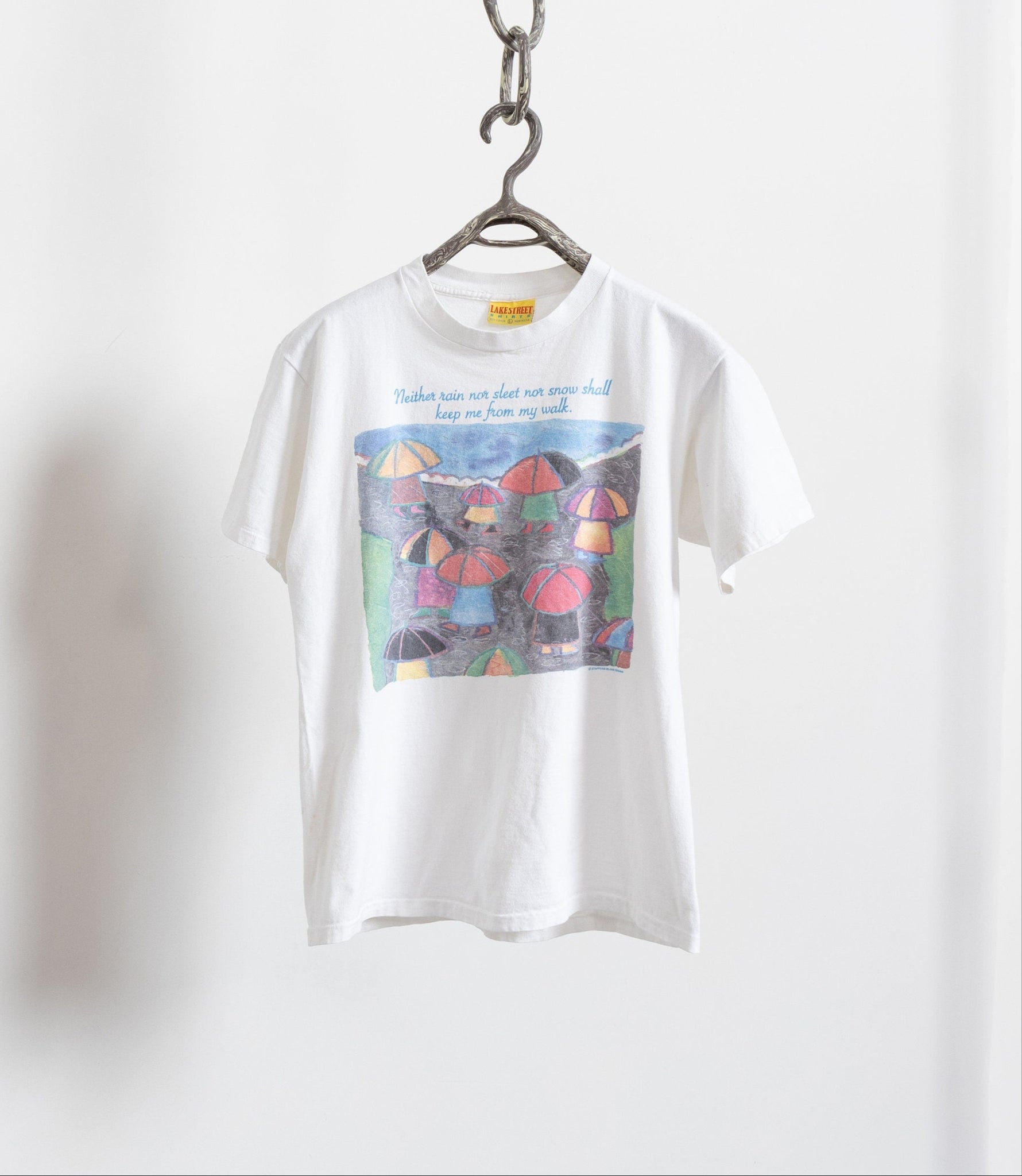 Vintage white cotton-knit tee with a watercolor graphic hanging against a white background.