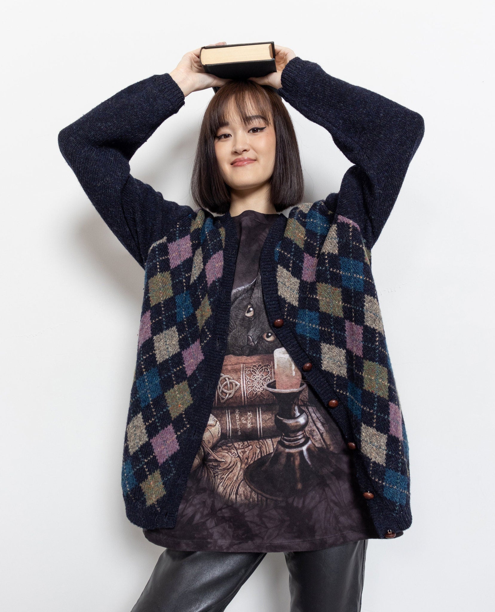 Person wearing a patterned vest over a graphic t-shirt on a white background