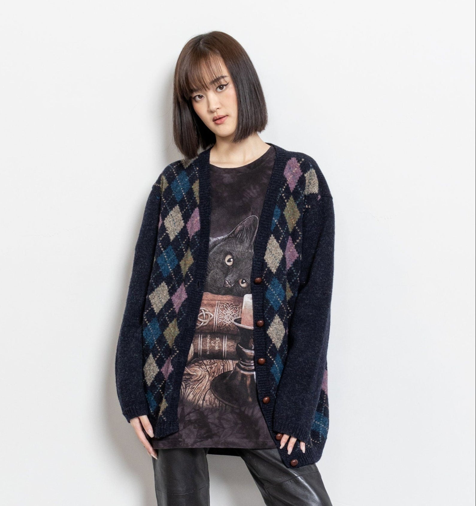 A person wearing a vintage 90's navy, blue, purple, and brown argyle wool cardigan with wooden buttons.