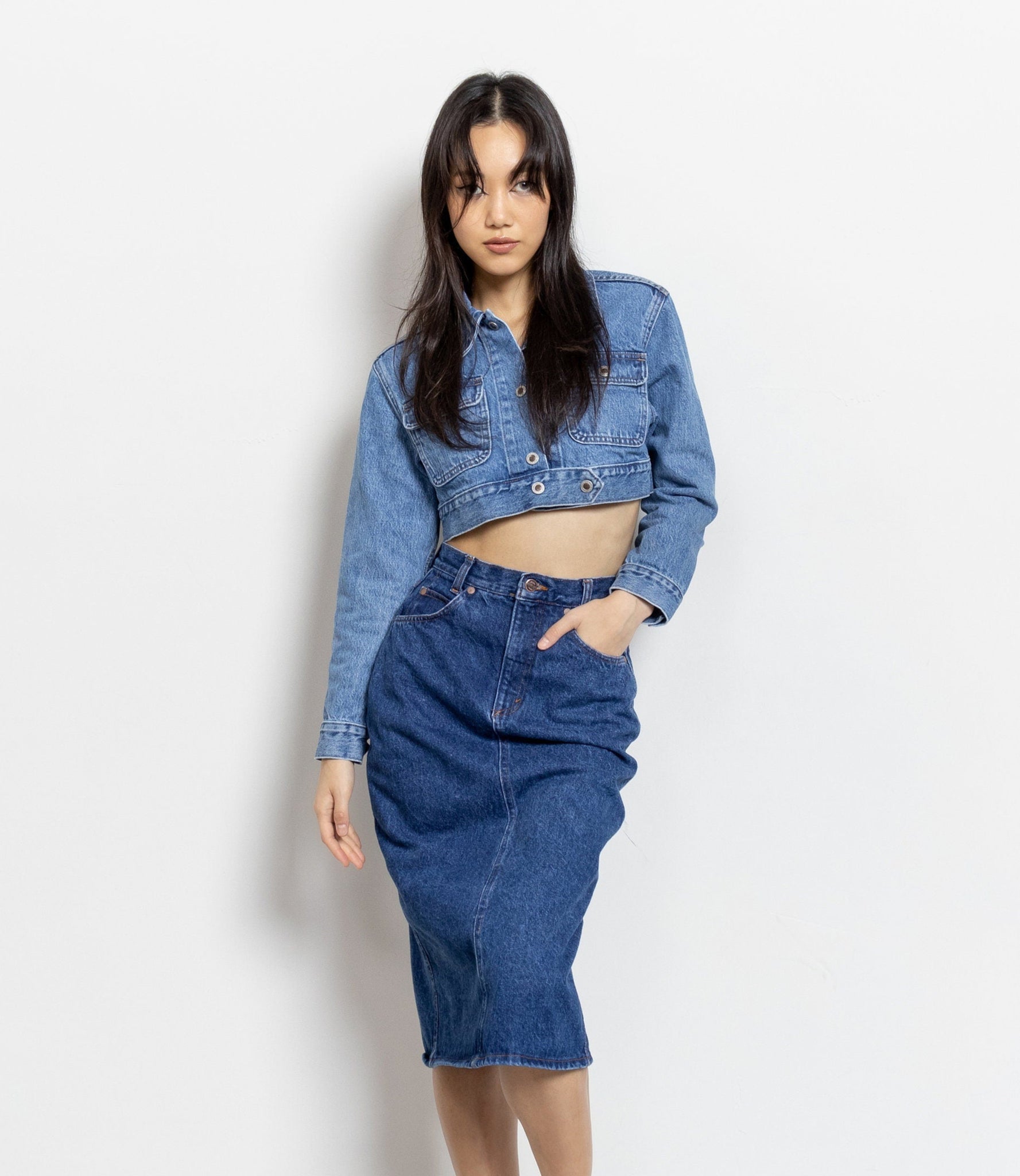 A person wearing a vintage United Colors Of Benetton denim high-rise pencil midi skirt with a crop denim jacket.