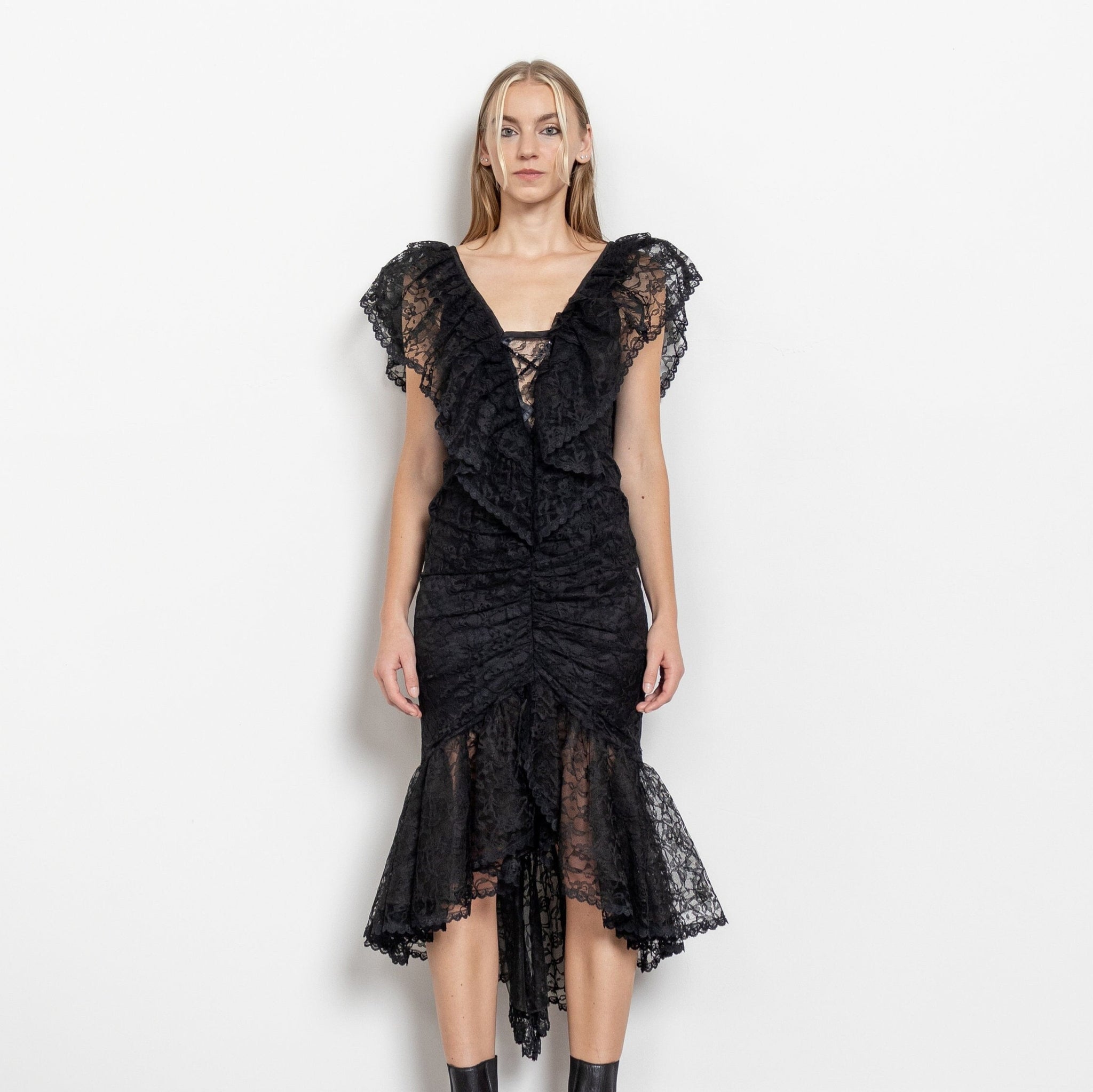 A vintage 80's black lace midi prom dress with a plunging open back design and a lining of sequins at the bodice. The dress explodes into a delicate lace trim at the hem.