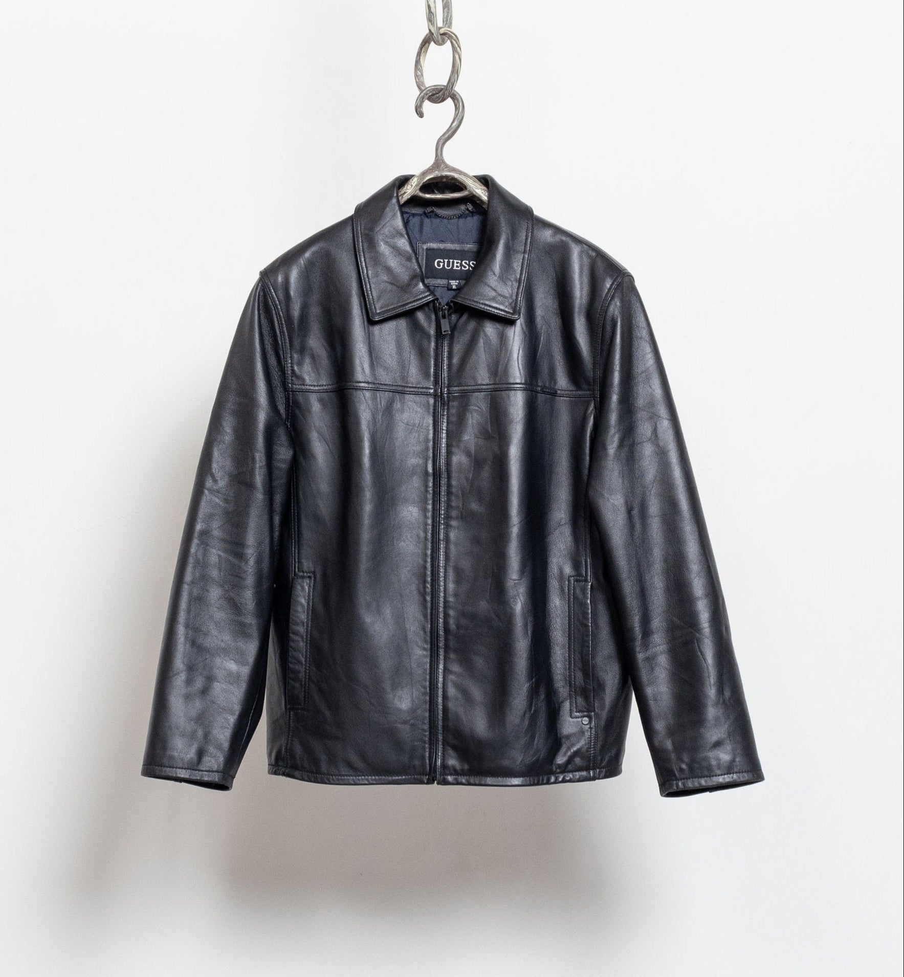 Black leather jacket on a hanger against a white background