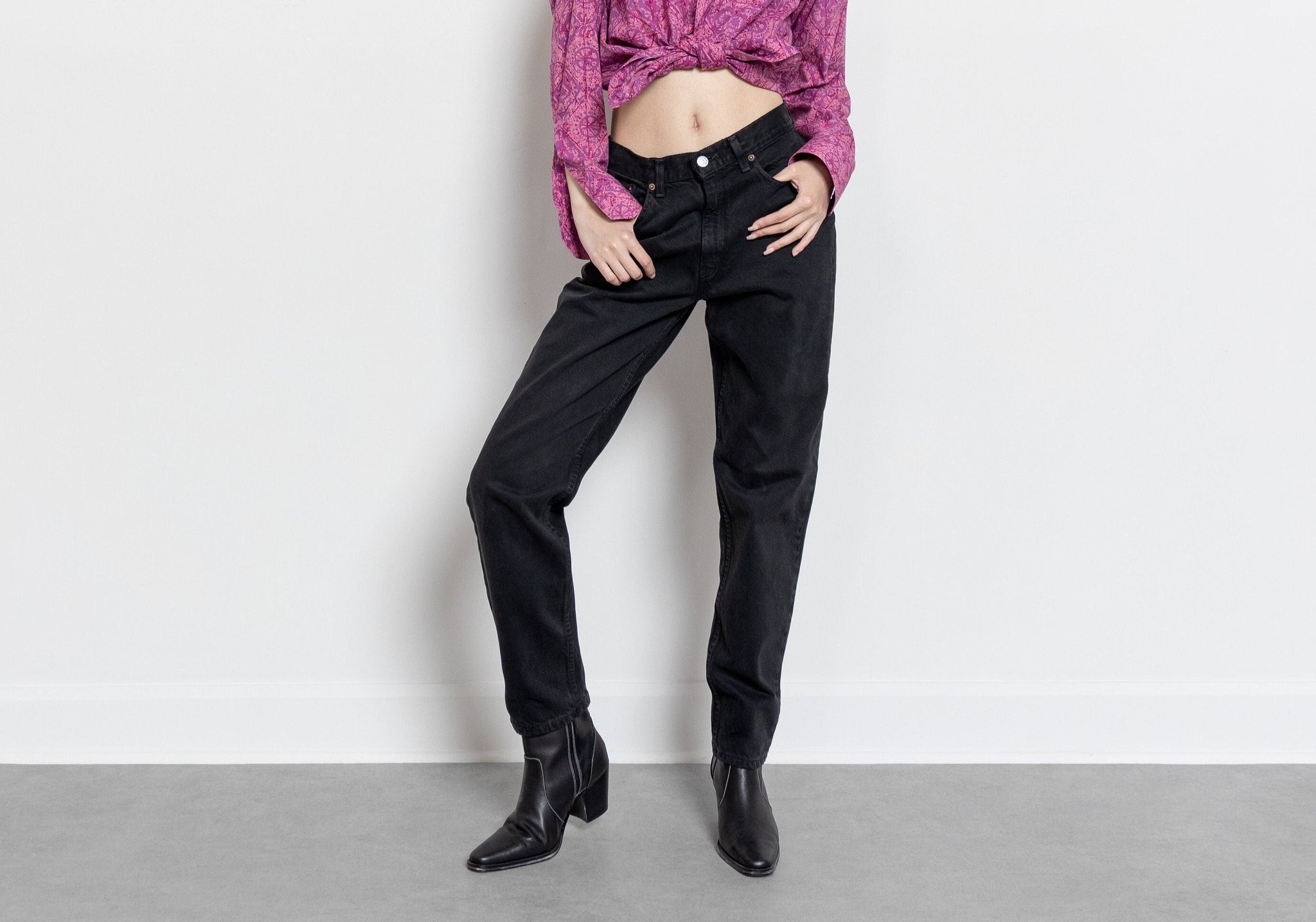 A person wearing high waist Levi's jeans in black, with a visible brand tag on the back waist.