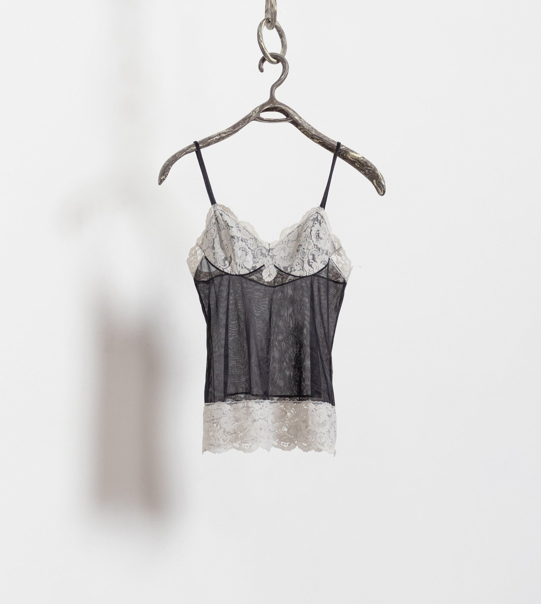 Black lace camisole on a hanger against a white background
