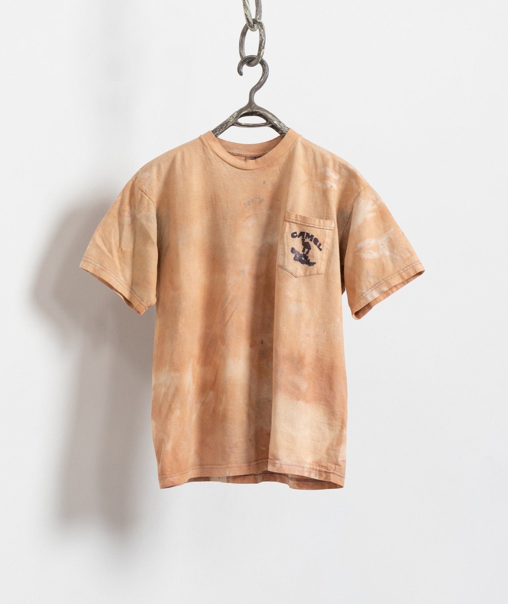 A beige and brown tie-dye t-shirt with a front breast pocket, hanging against a white background.