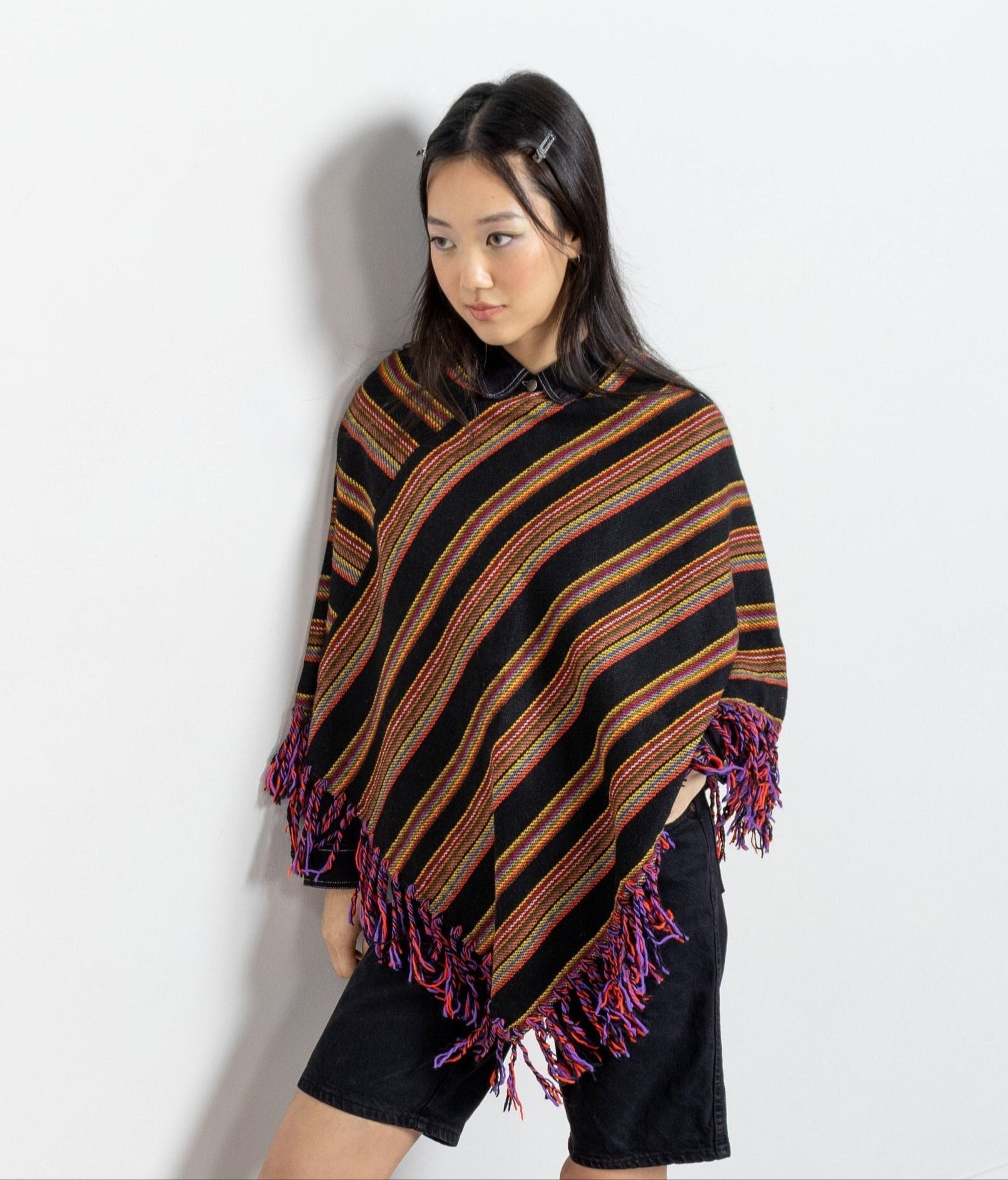 Woman wearing a striped poncho with tassels on a white background