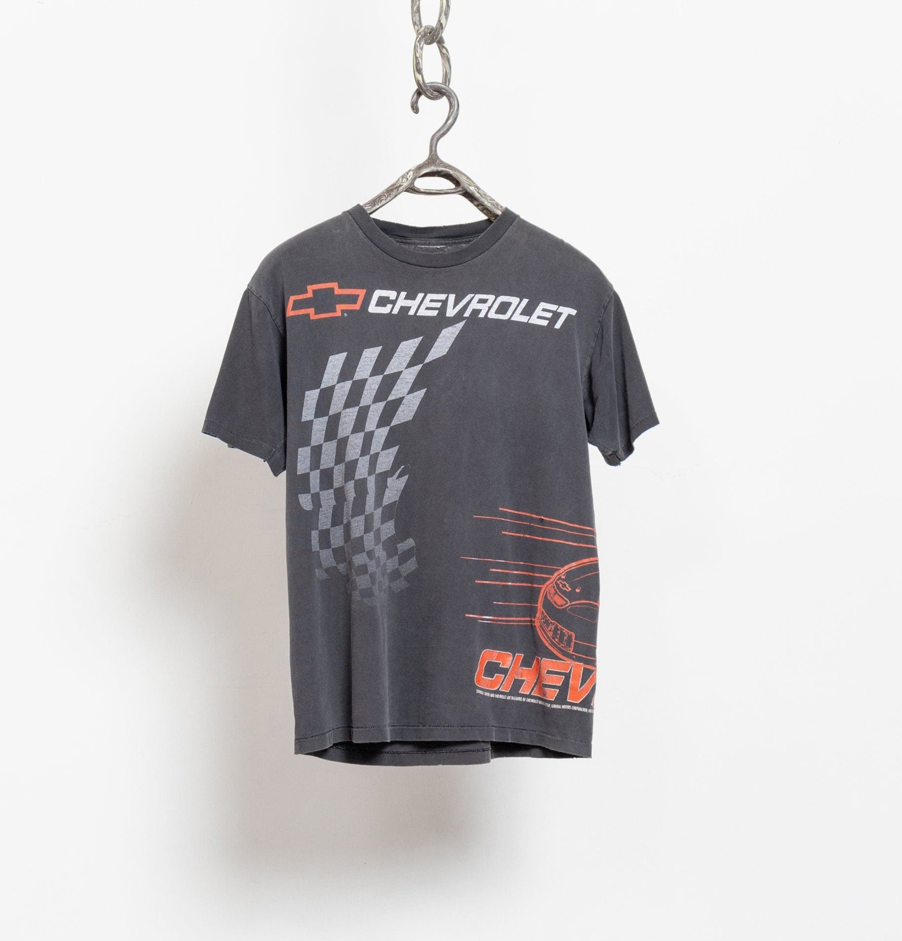 A black t-shirt with Chevrolet branding and graphic prints, hanging on a hanger against a white background.