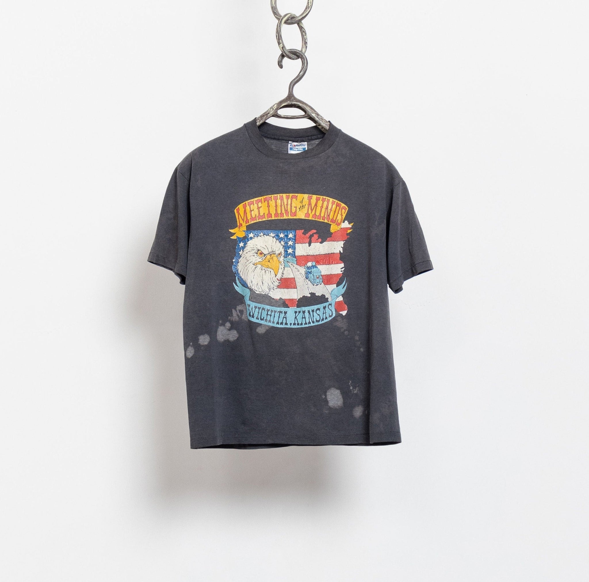 Vintage t-shirt with graphic design on a hanger against a white background
