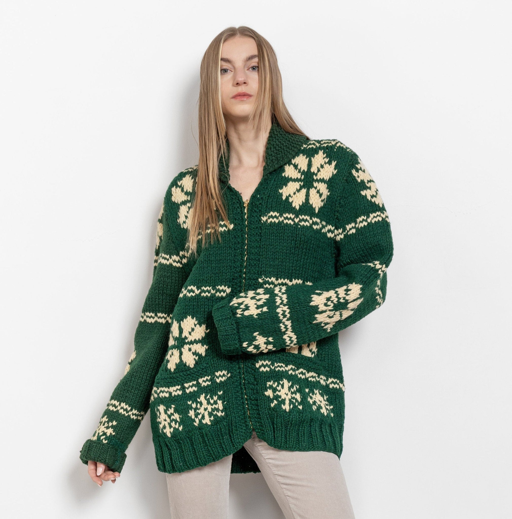 Woman wearing a green knitted cardigan with white patterns on a white background