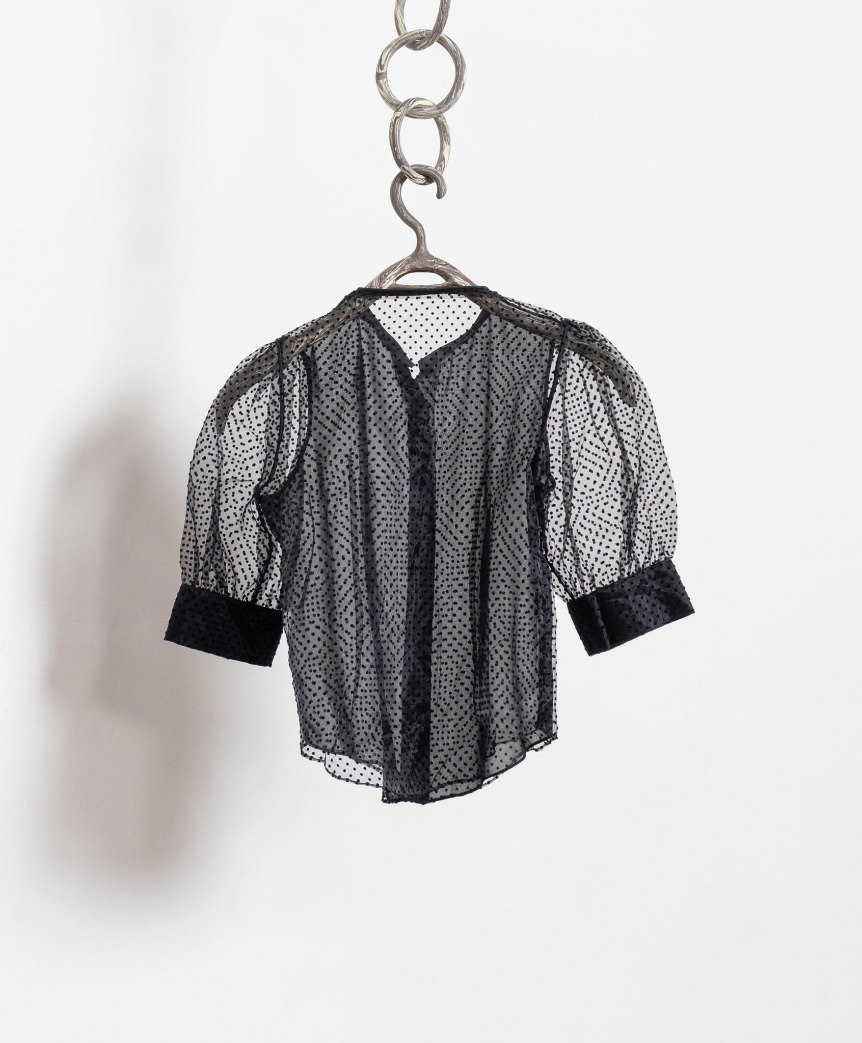 Black mesh shirt on a hanger against a white background