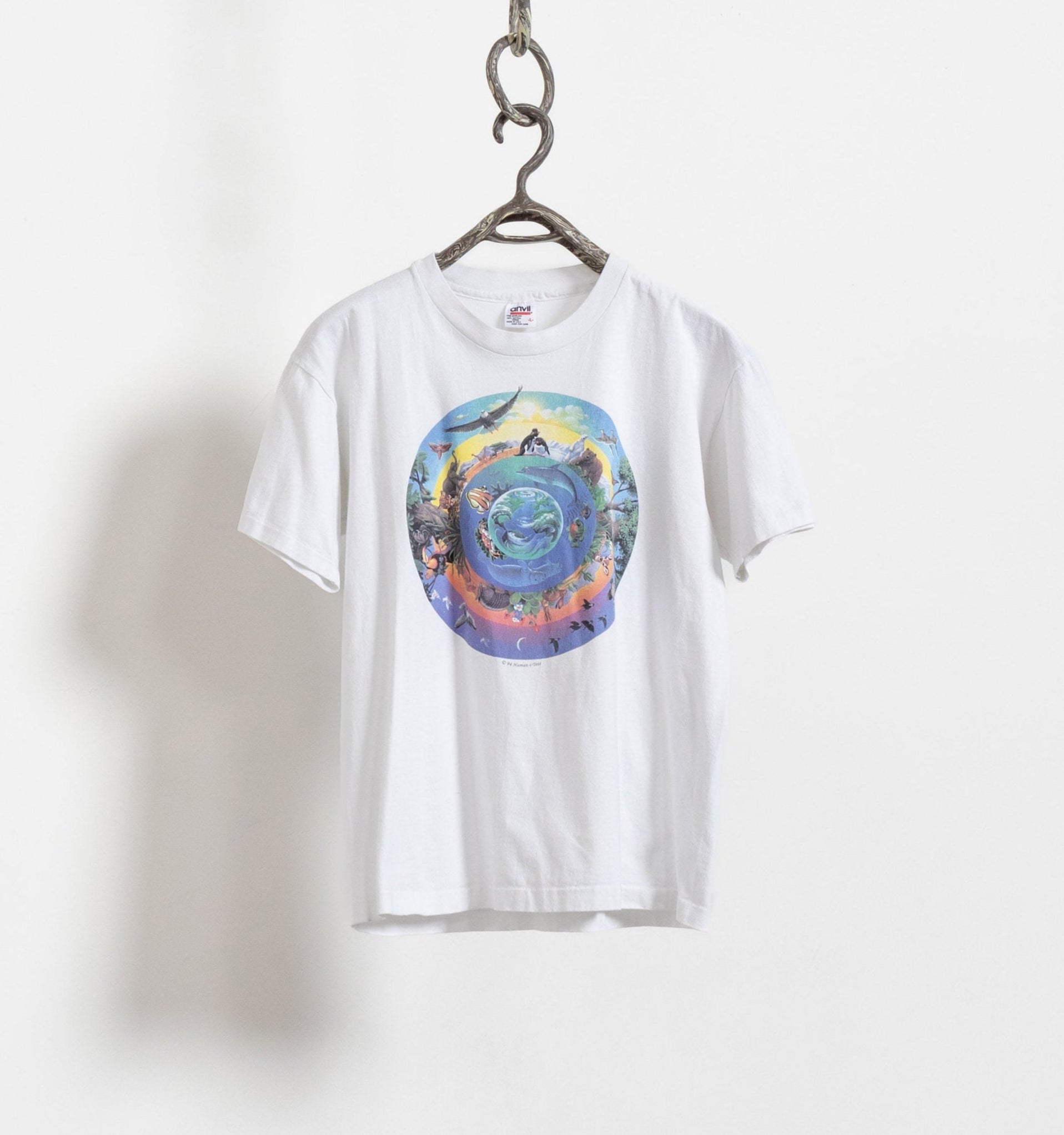 White cotton t-shirt with a central graphic of the earth and various animals around it, displayed on a hanger against a white background.
