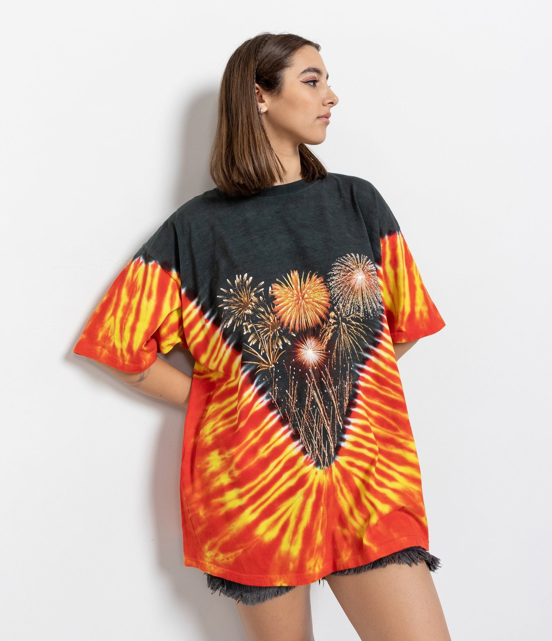 Person wearing a tie-dye t-shirt with fireworks design on a white background