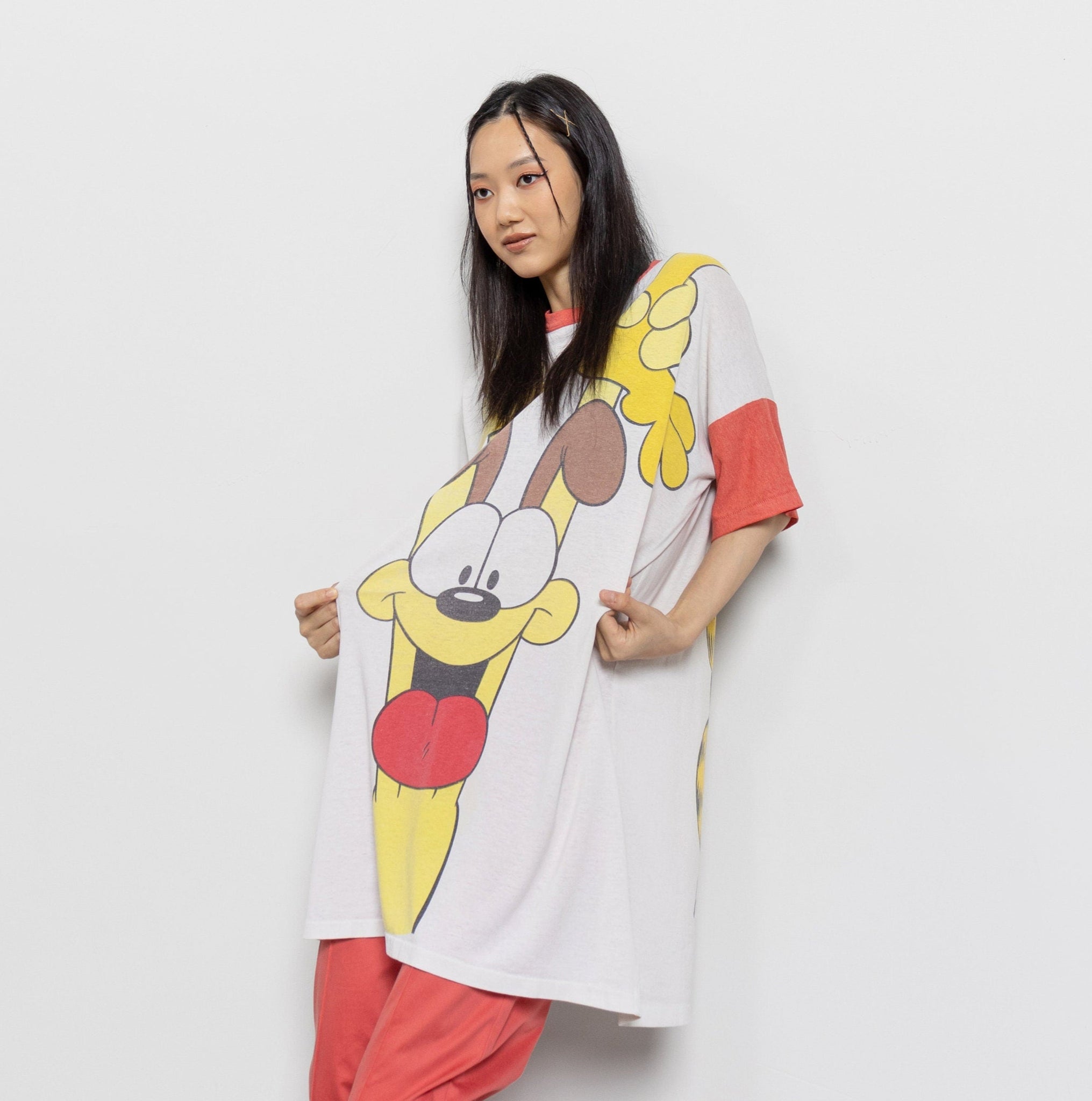 A person wearing a graphic t-shirt with a cartoon character resembling Garfield and a dog resembling Odie. The shirt has a 1978 Garfield copyright and Jim Davis signature.