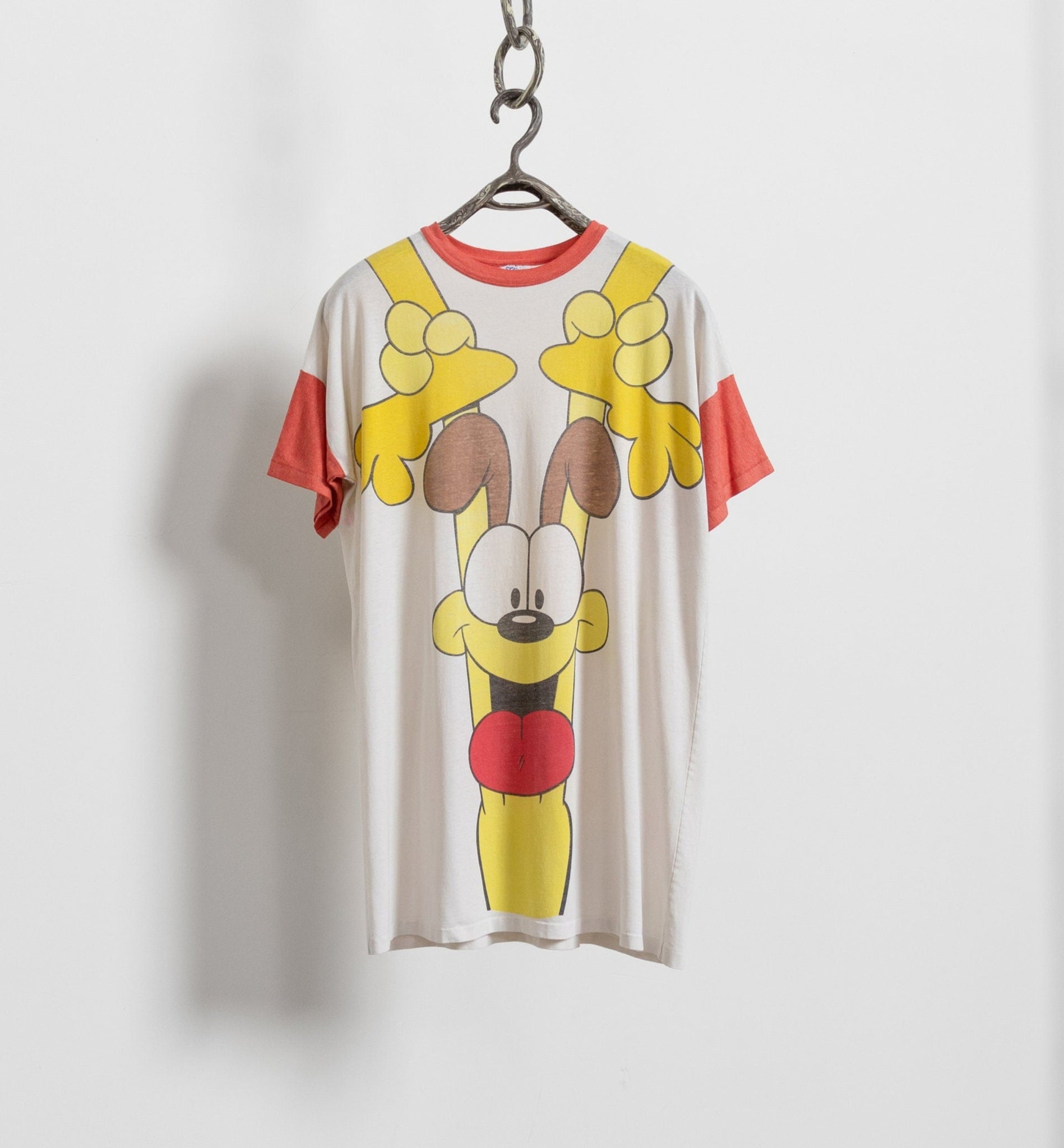 T-shirt with cartoon character design on a hanger against a white background