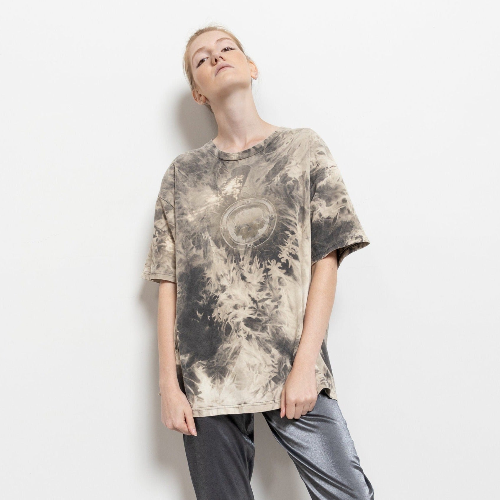 A person wearing a tie-dye Harley Davidson t-shirt with a skull graphic, in a standing pose against a white background.