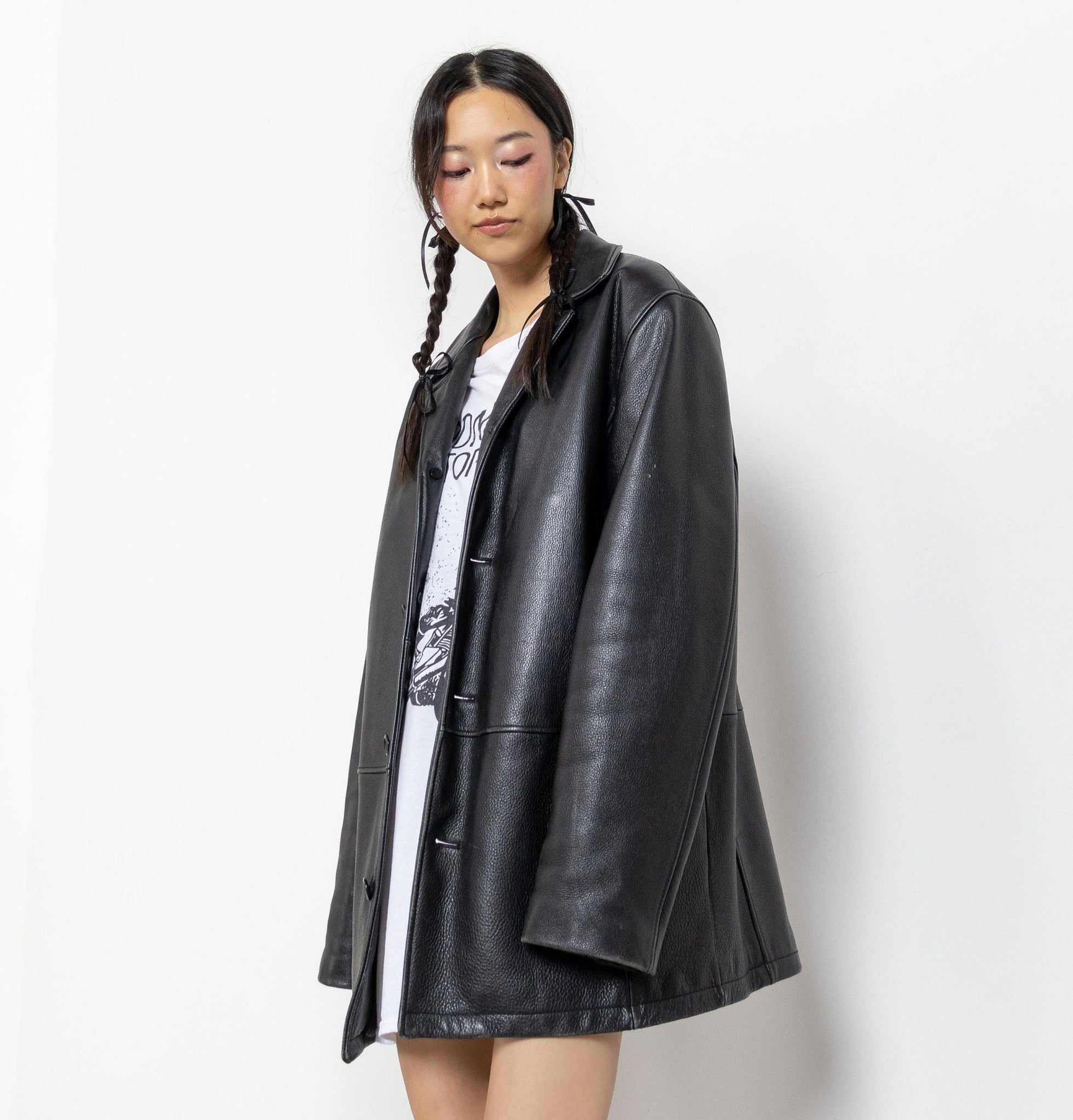 Person wearing a black leather coat over a graphic t-shirt on a white background