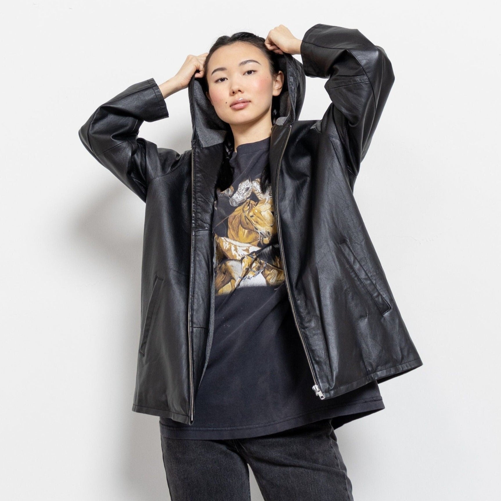 Person wearing a black raincoat over a graphic t-shirt on a white background