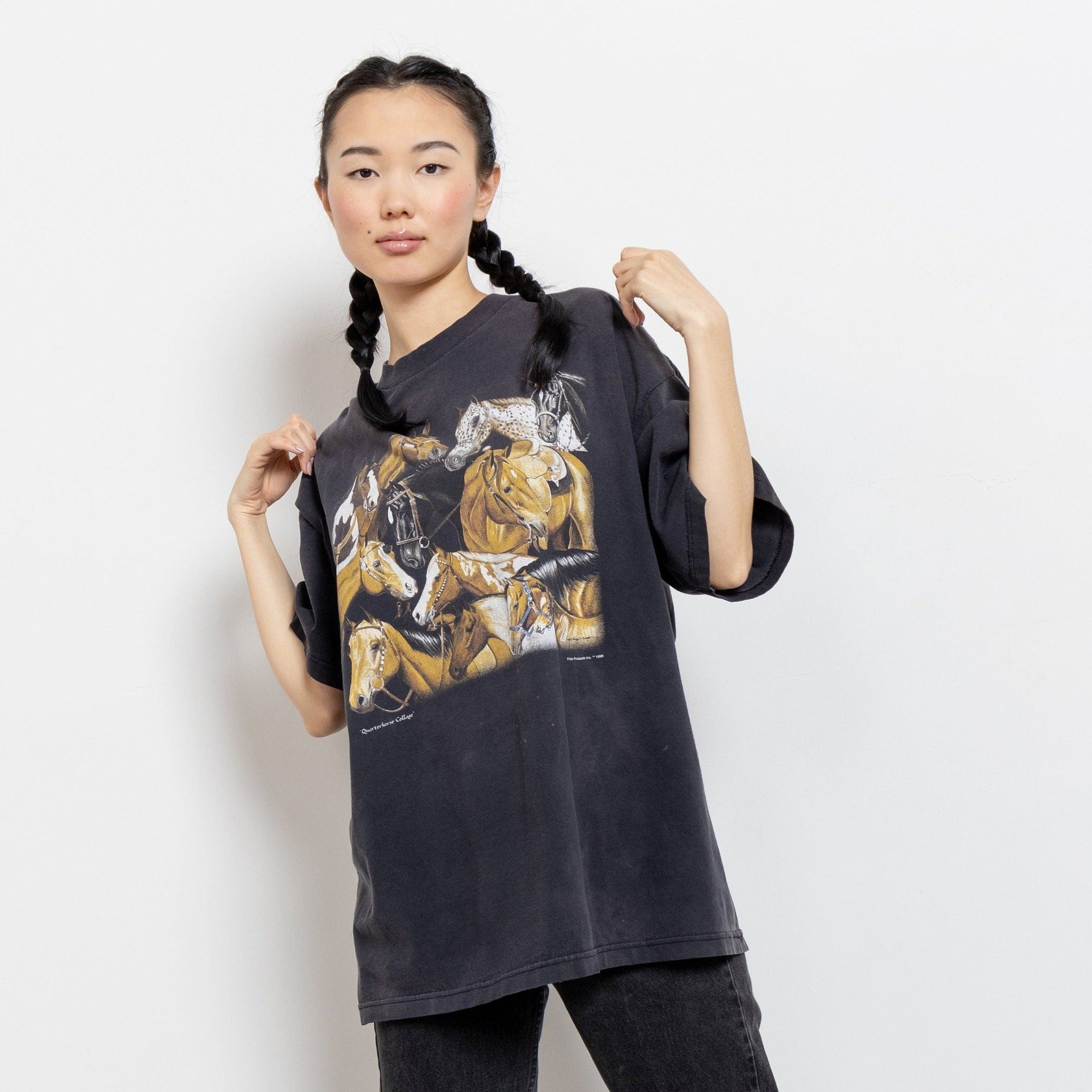A person modeling a vintage black t-shirt with a horse graphic.