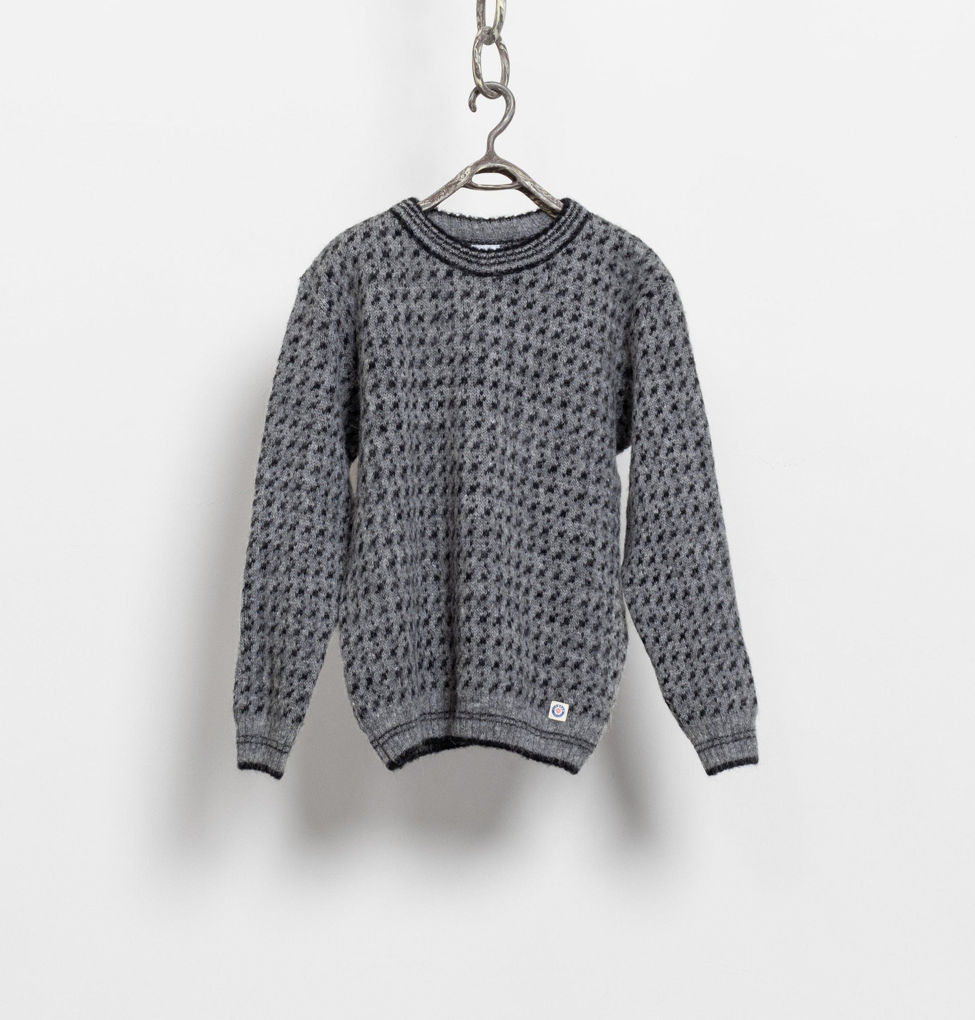 A vintage 90's traditional Icelandic 100% wool sweater, hanging from a chain, with a grey knit pattern.