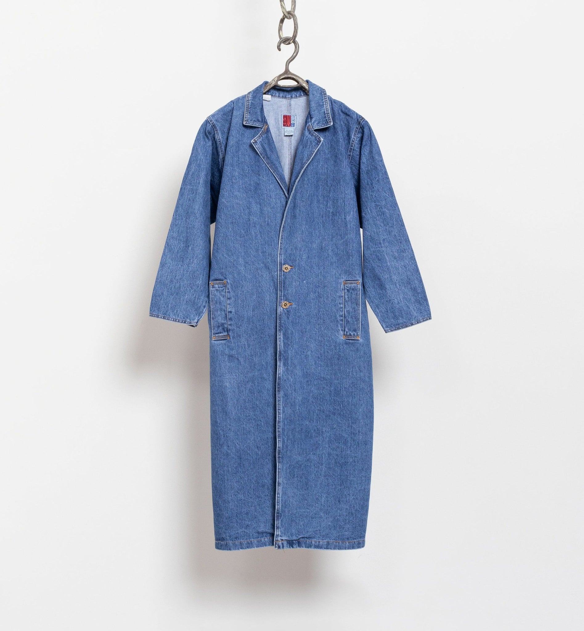 Blue denim coat on a hanger against a white background