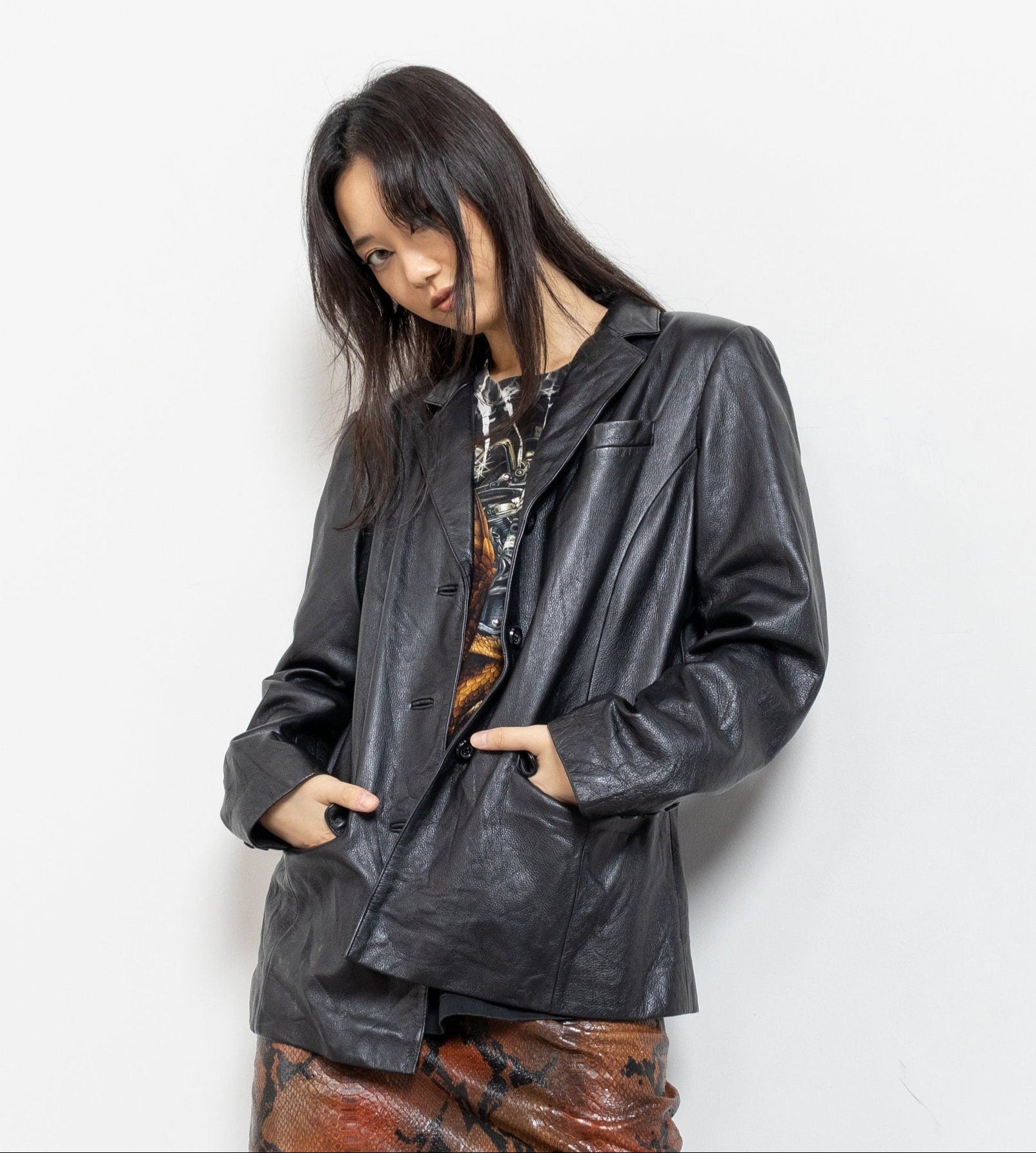 Woman wearing a black leather jacket and brown skirt against a white background