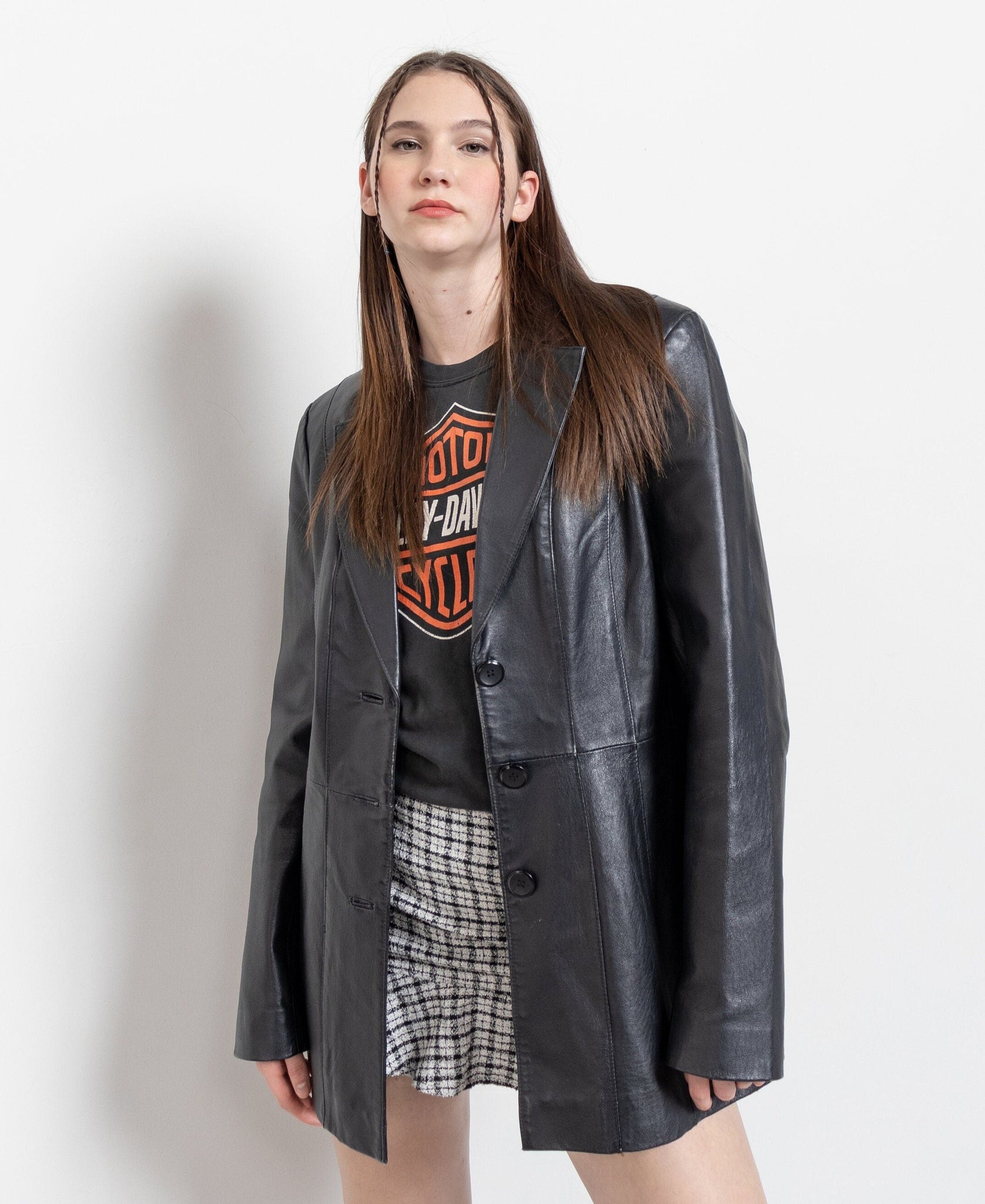 Person wearing a gray leather jacket over a graphic t-shirt on a white background