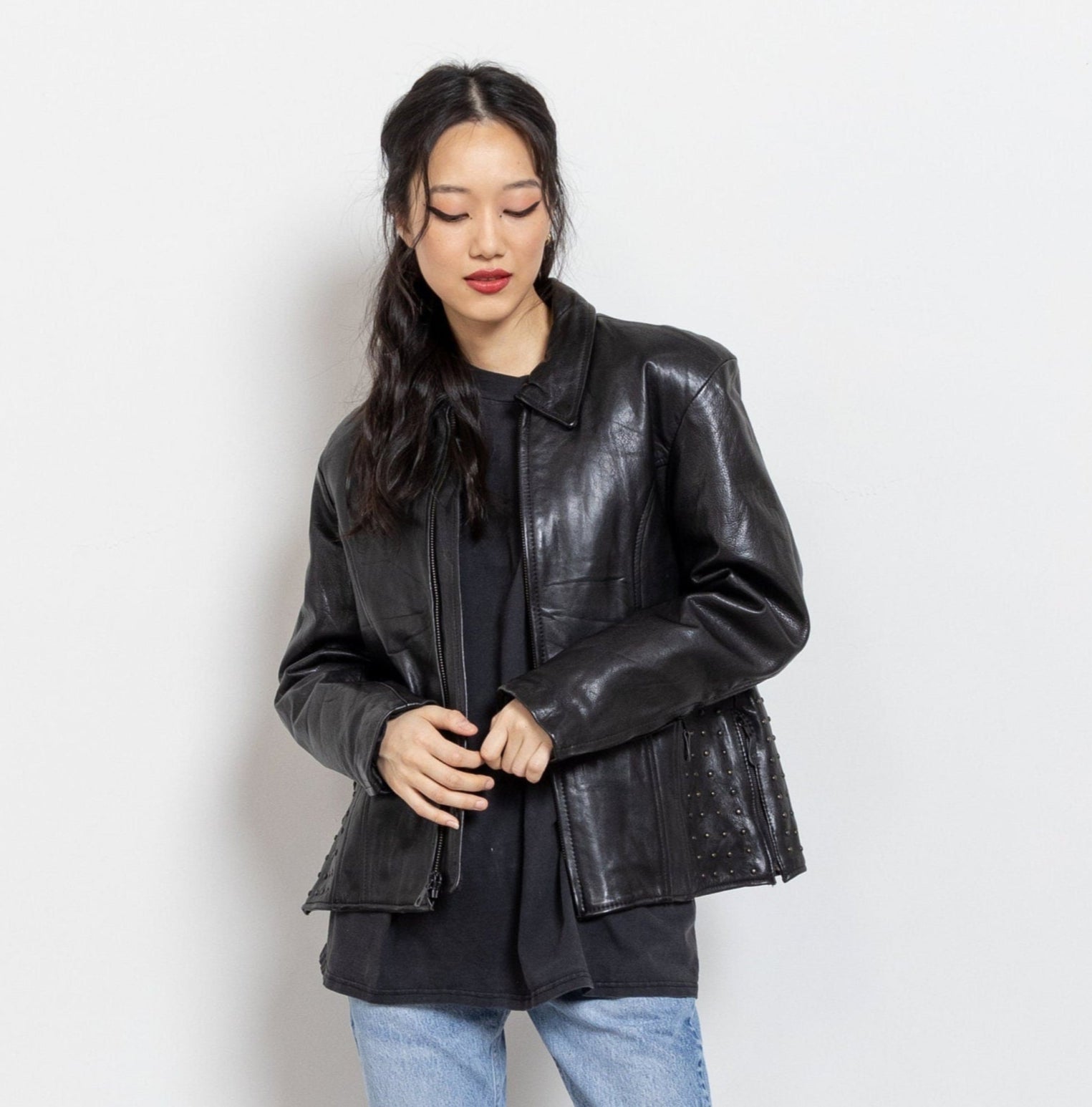 Woman wearing a black leather jacket and jeans on a white background